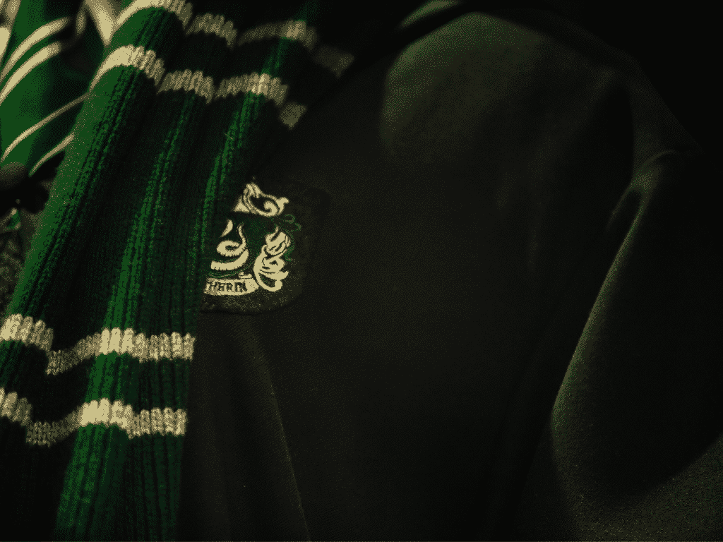 A close up of a slytherin scarf and badge - Slytherin
