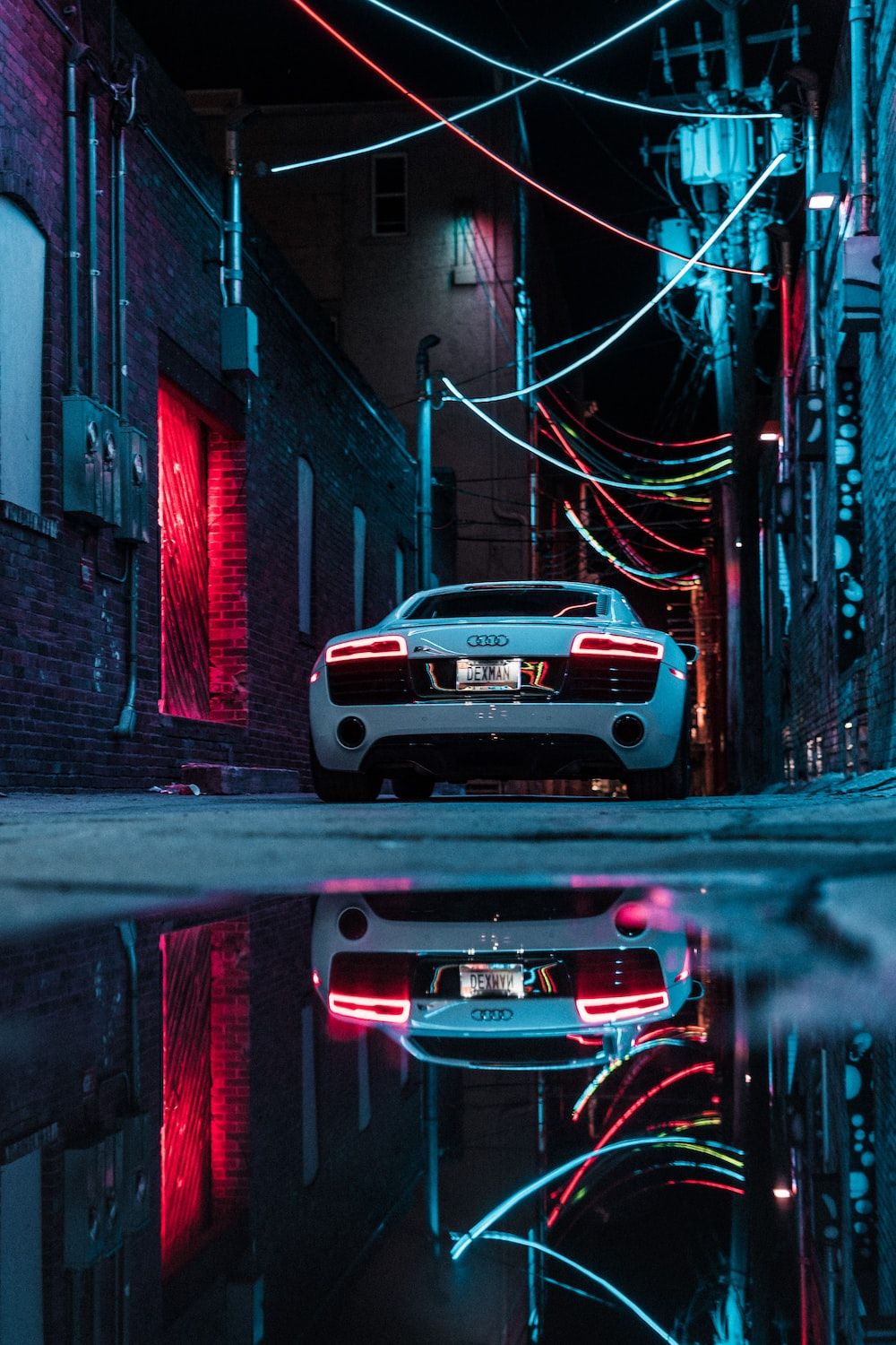 A white car parked in a dark alley with neon lights. - Cars