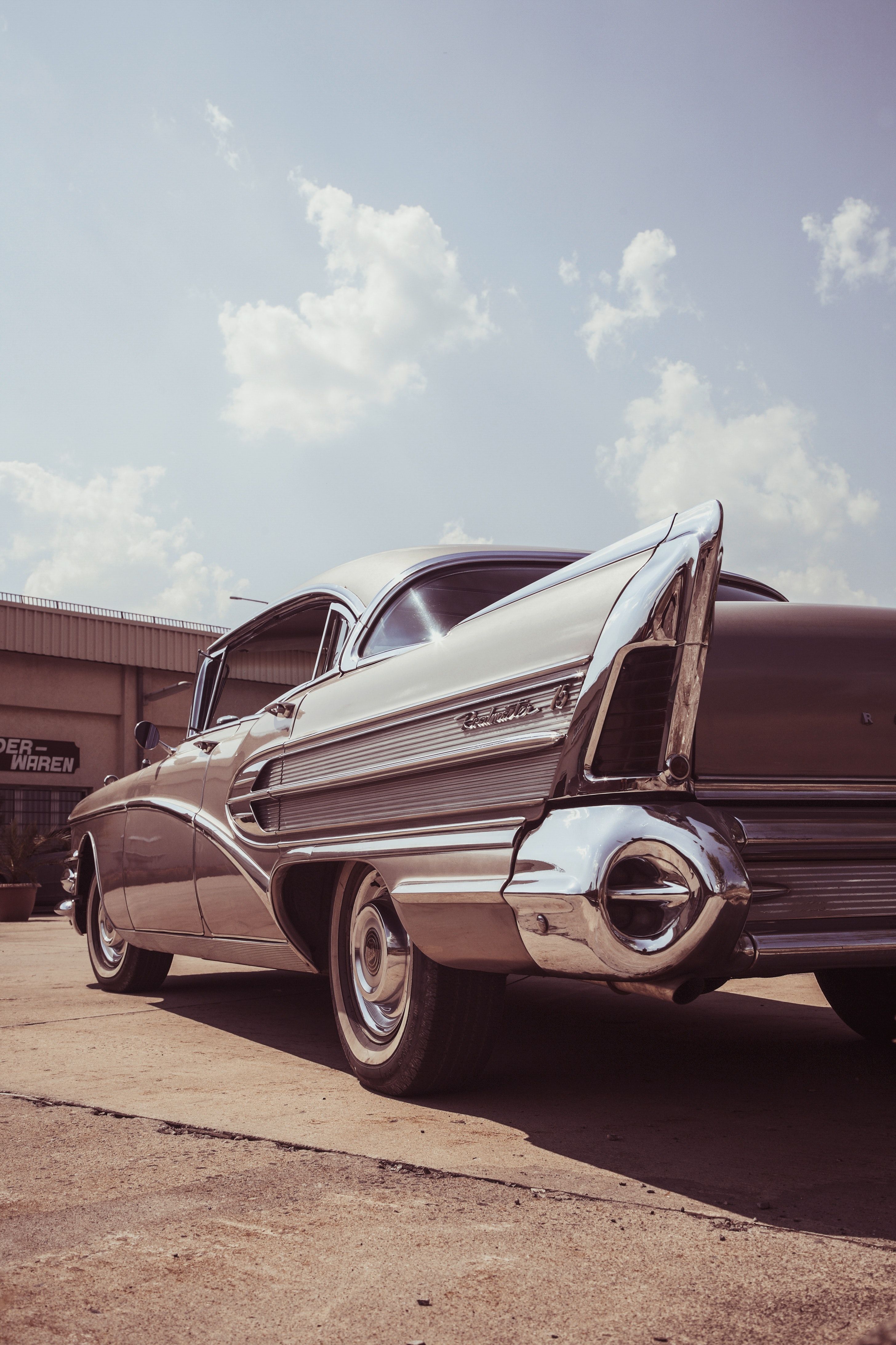 A black and white classic car is parked in a lot. - Cars