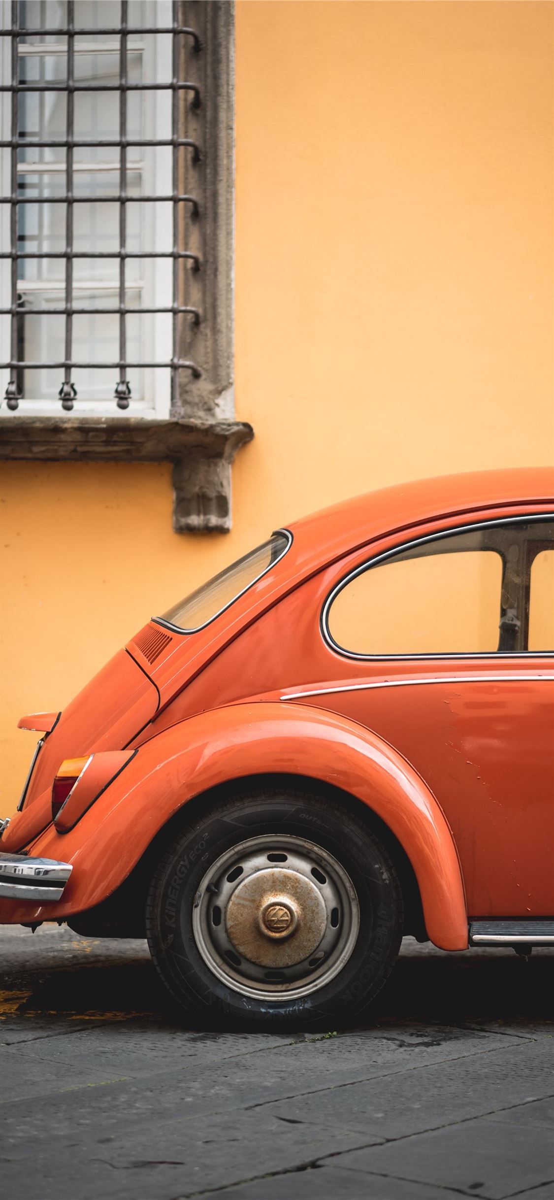 An orange vintage car parked on the side of the street - Cars