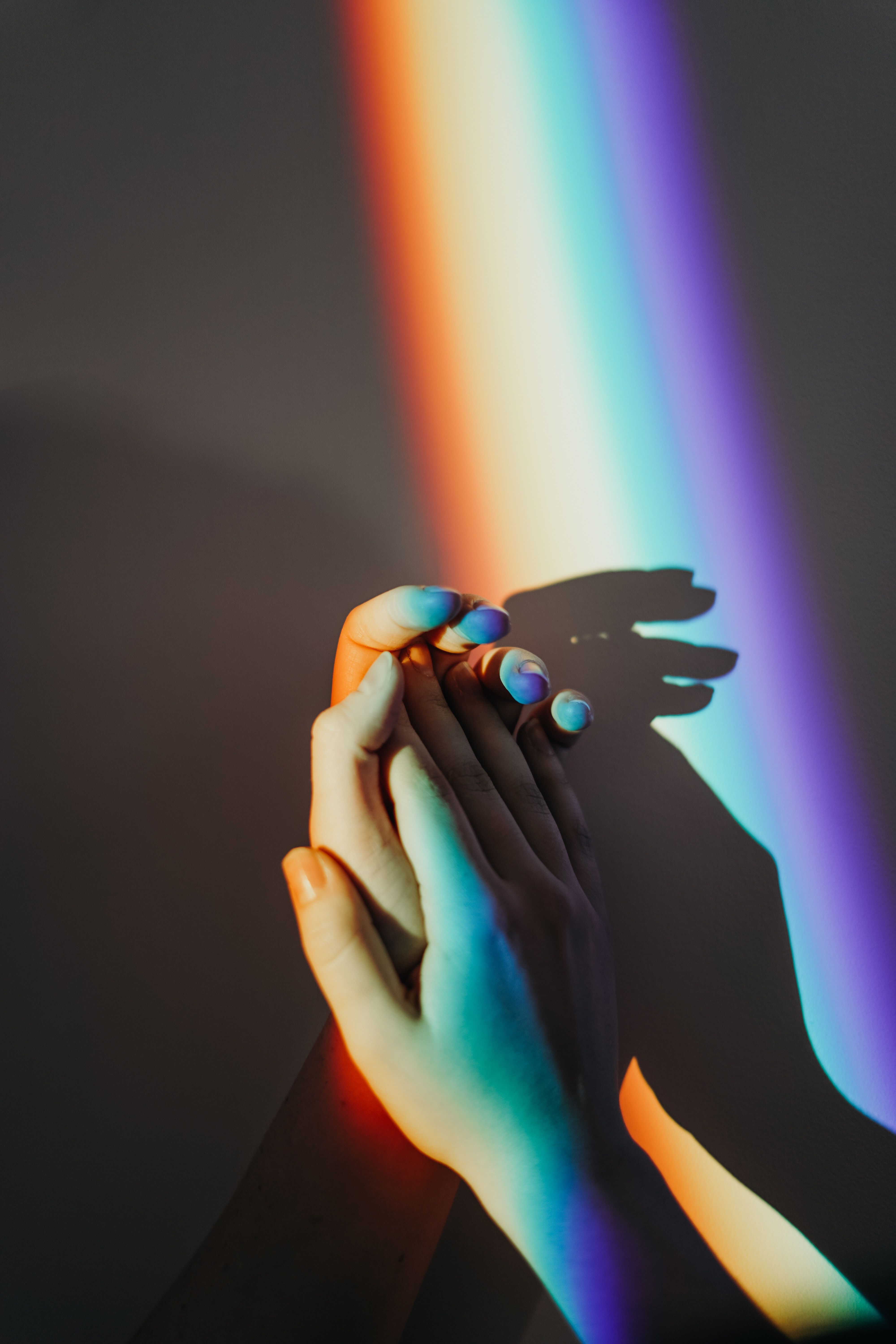 A hand holding another person's hands with rainbow light - Pride, gay