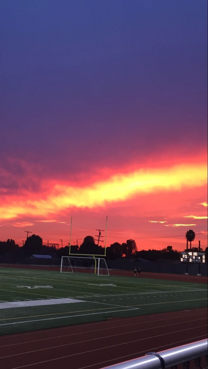 A soccer field with the sun setting in front of it - Soccer, sunset