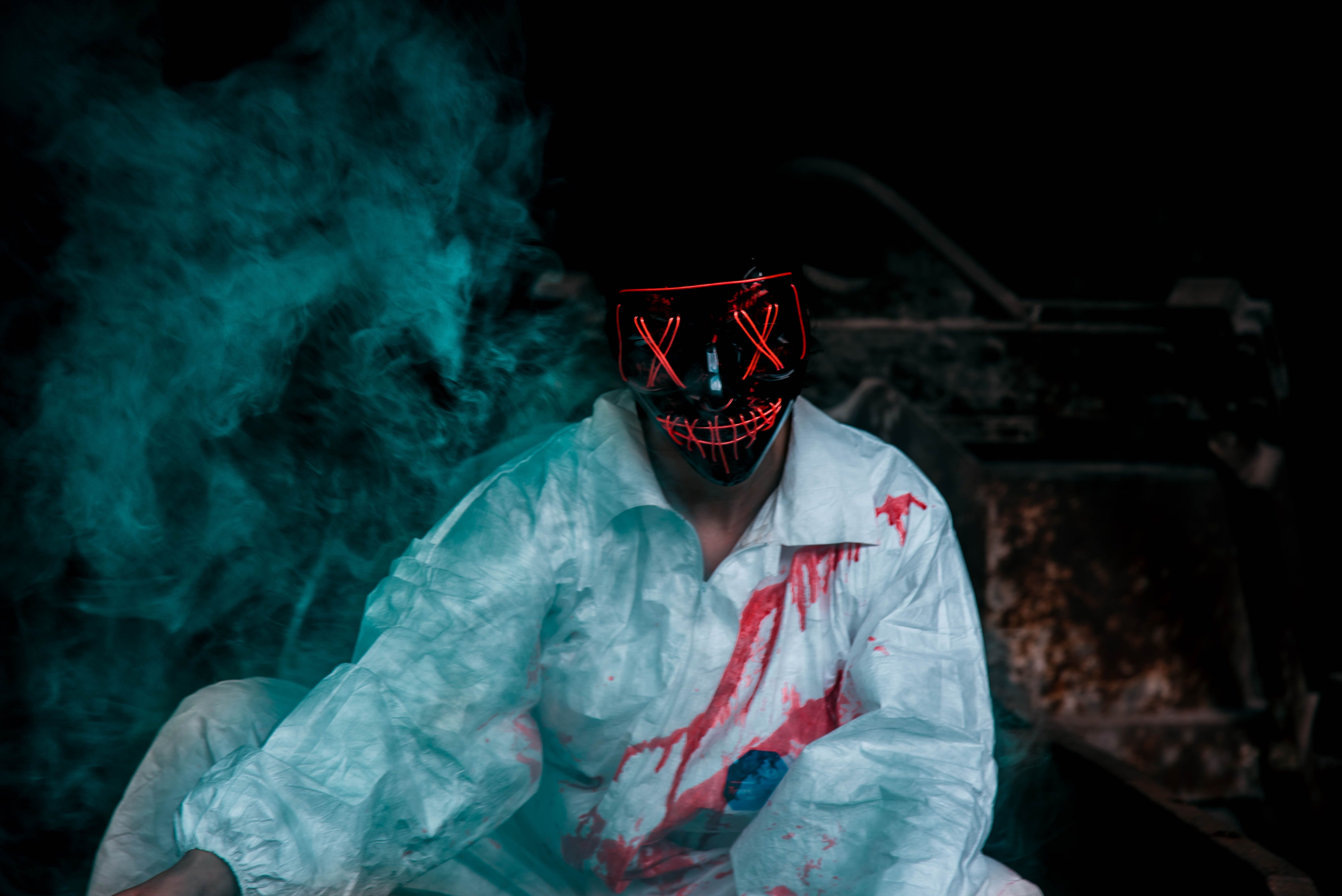 A scary clown with a red LED mask and blood on his shirt - Blood