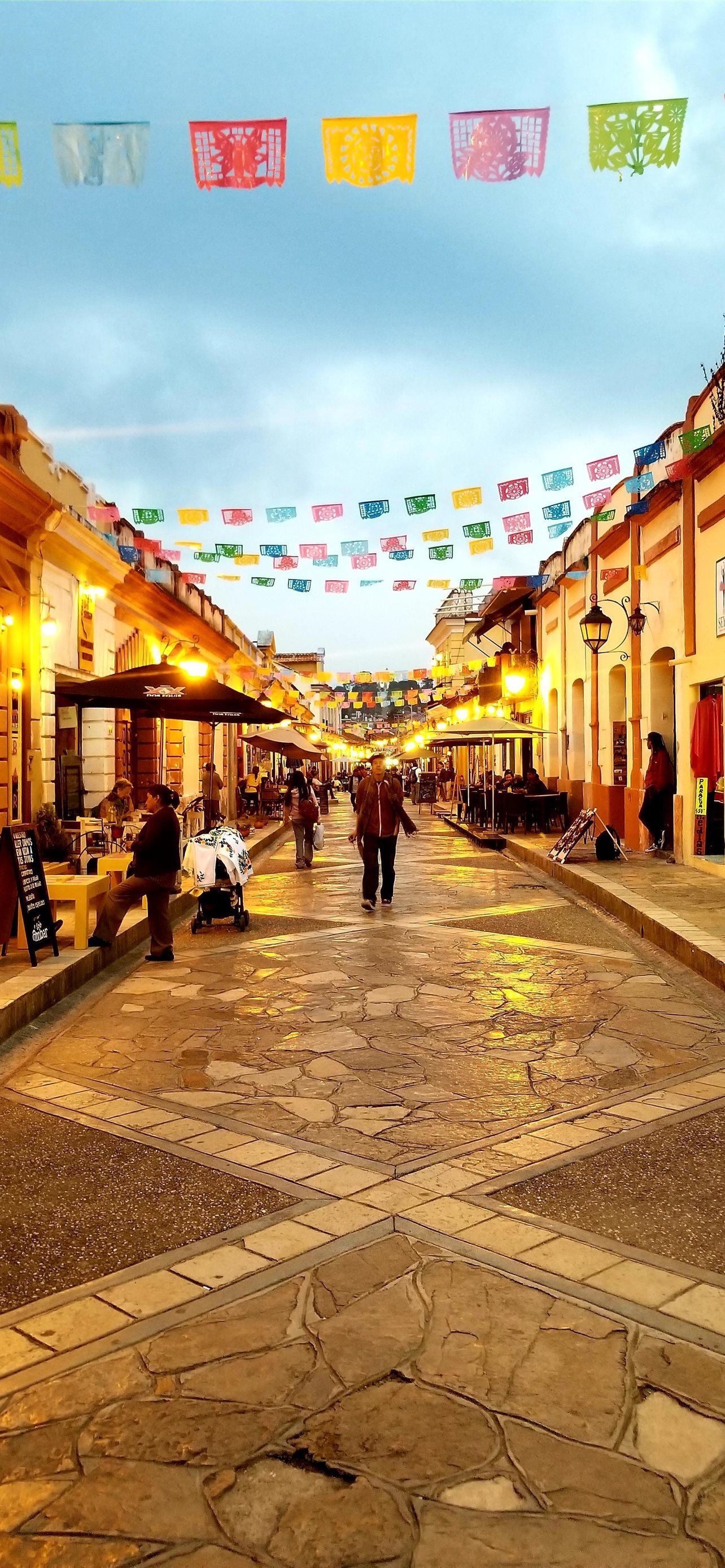 A street with people walking and flags hanging - Mexico