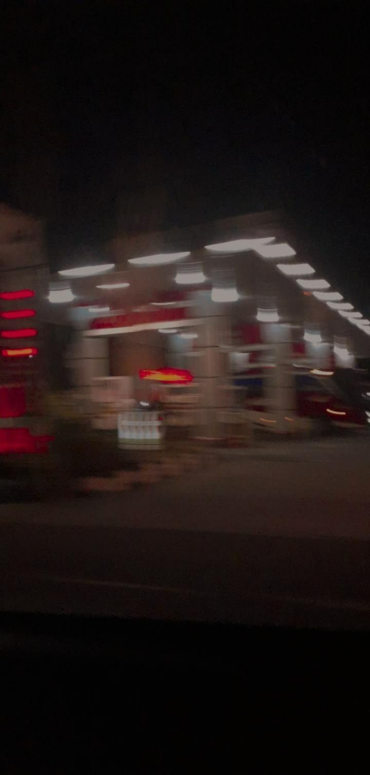 A gas station at night with cars in the parking lot - Blurry