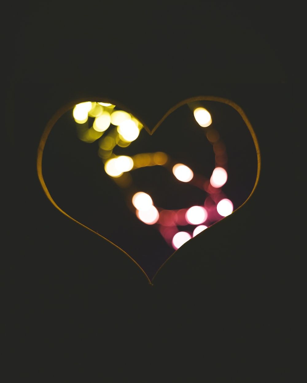 A heart shape made out of lights in the dark. - Black heart