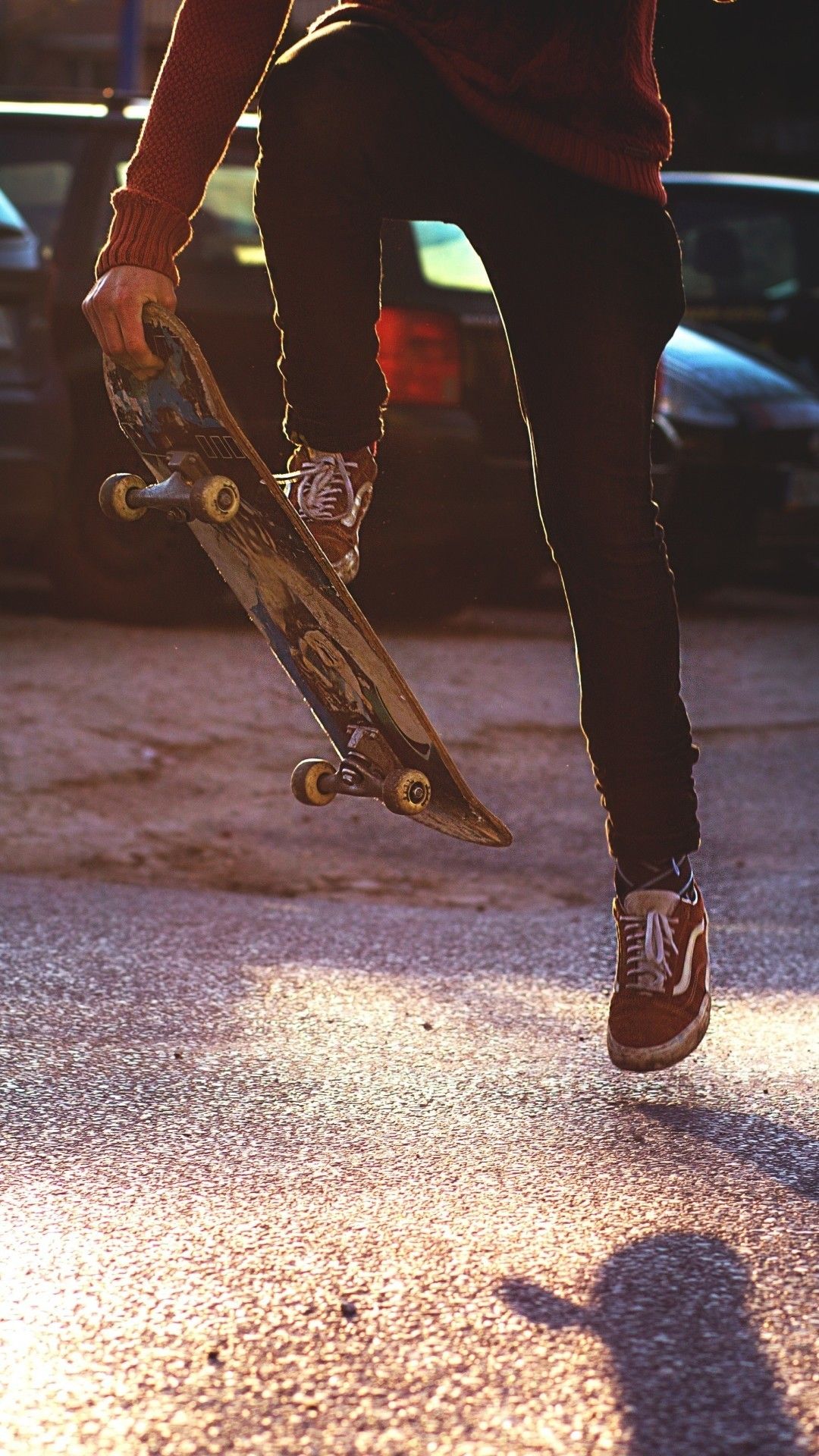 A person holding a skateboard in one hand and jumping in the air with the other - Skate