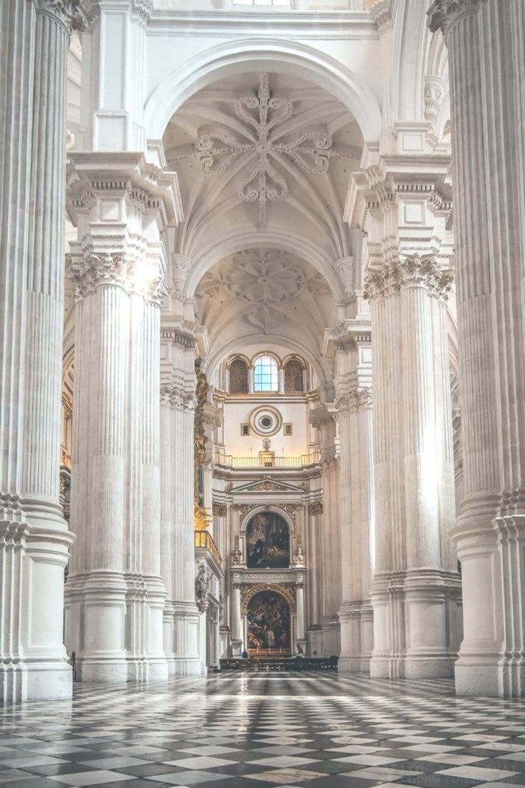 The inside of a cathedral with a black and white checkered floor and high white columns. - Architecture