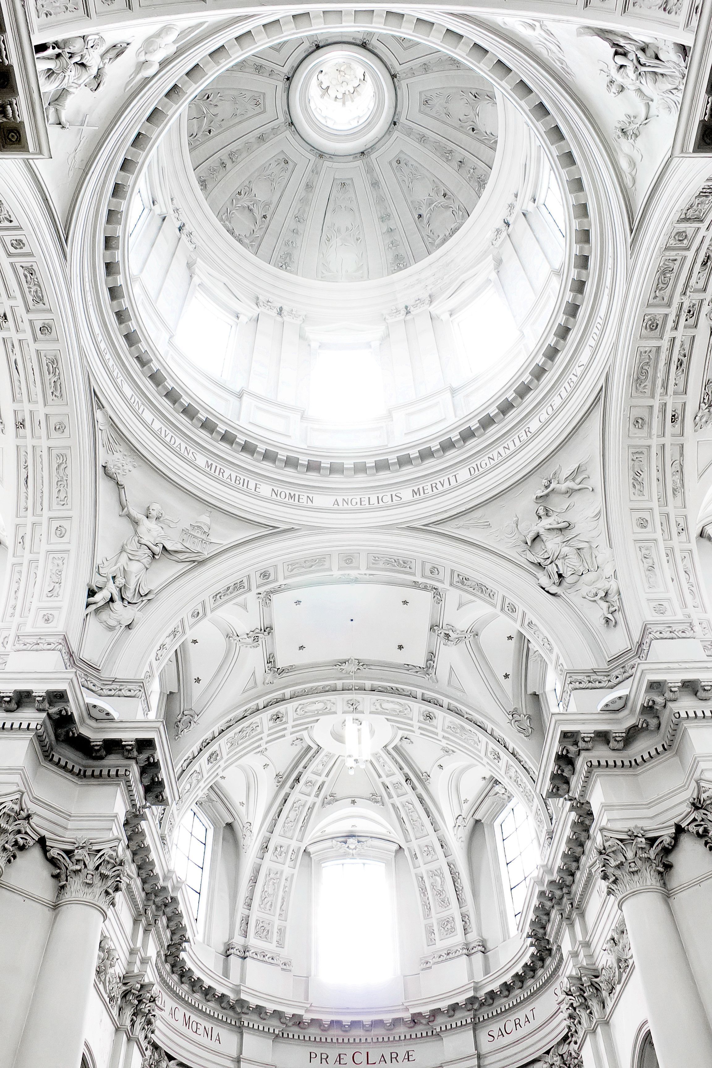 The ceiling of a white church with a large dome. - Architecture