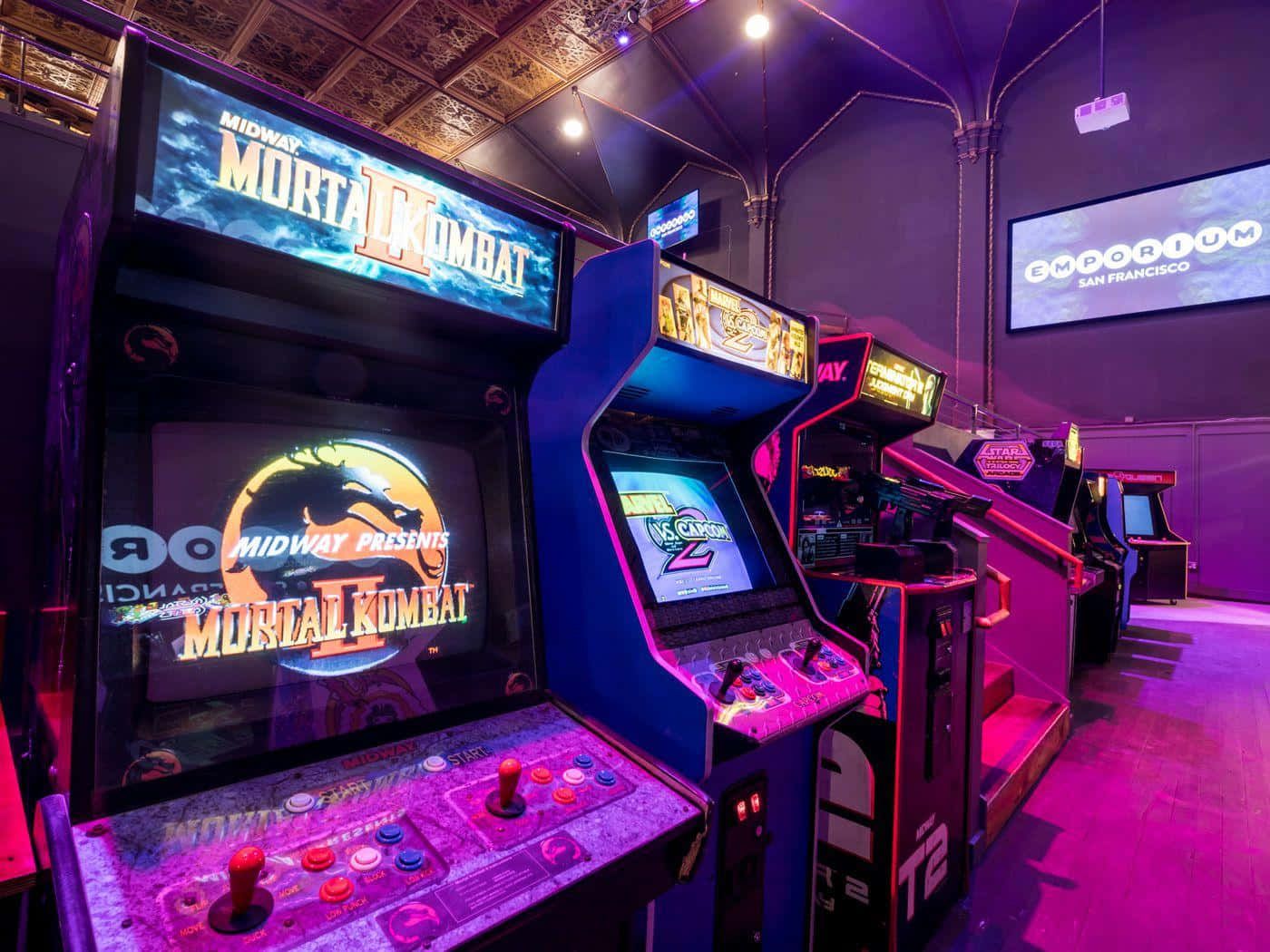 A row of video games, including Mortal Kombat, in a dark room with purple lighting. - Arcade