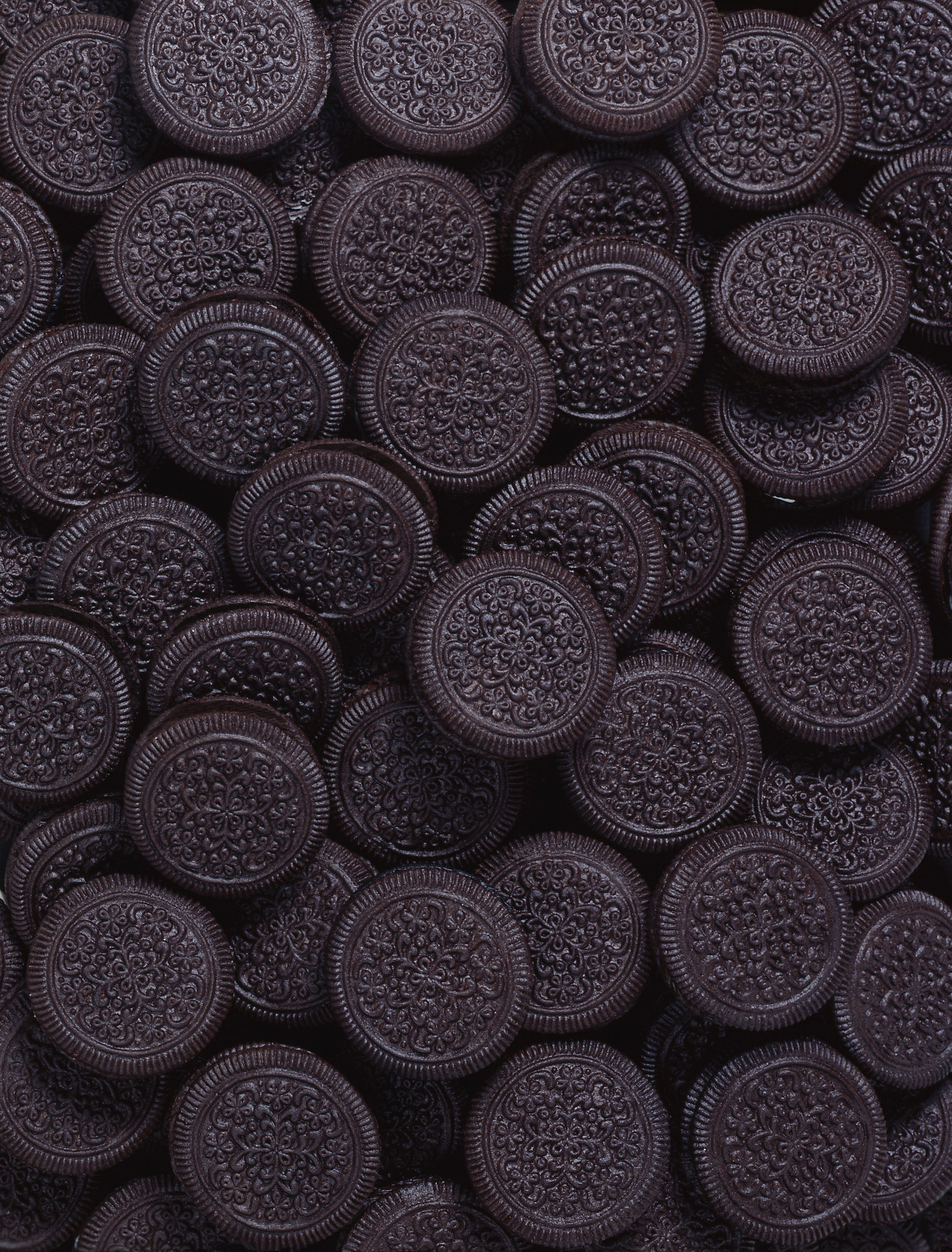 A close up of chocolate sandwich cookies in a pile. - Oreo