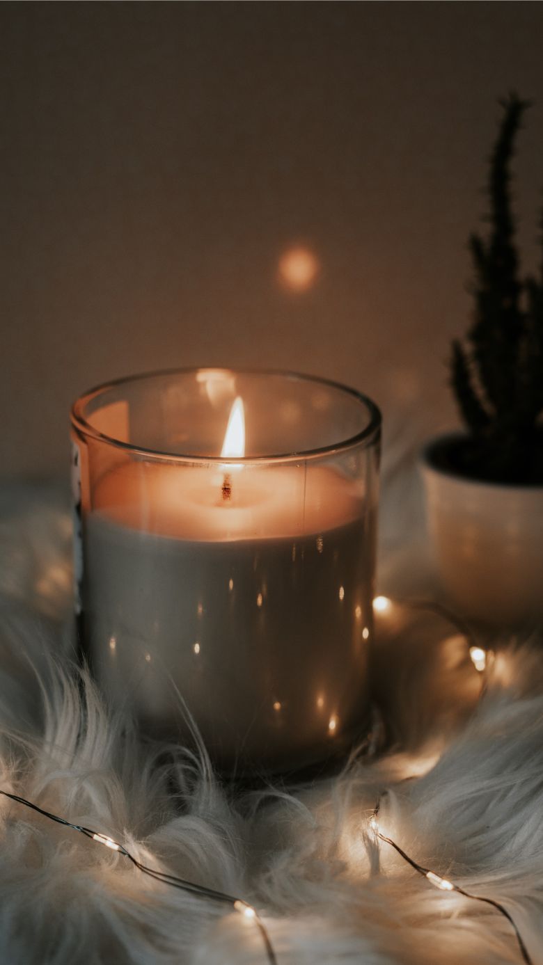 A candle sitting on top of some fur - Cozy