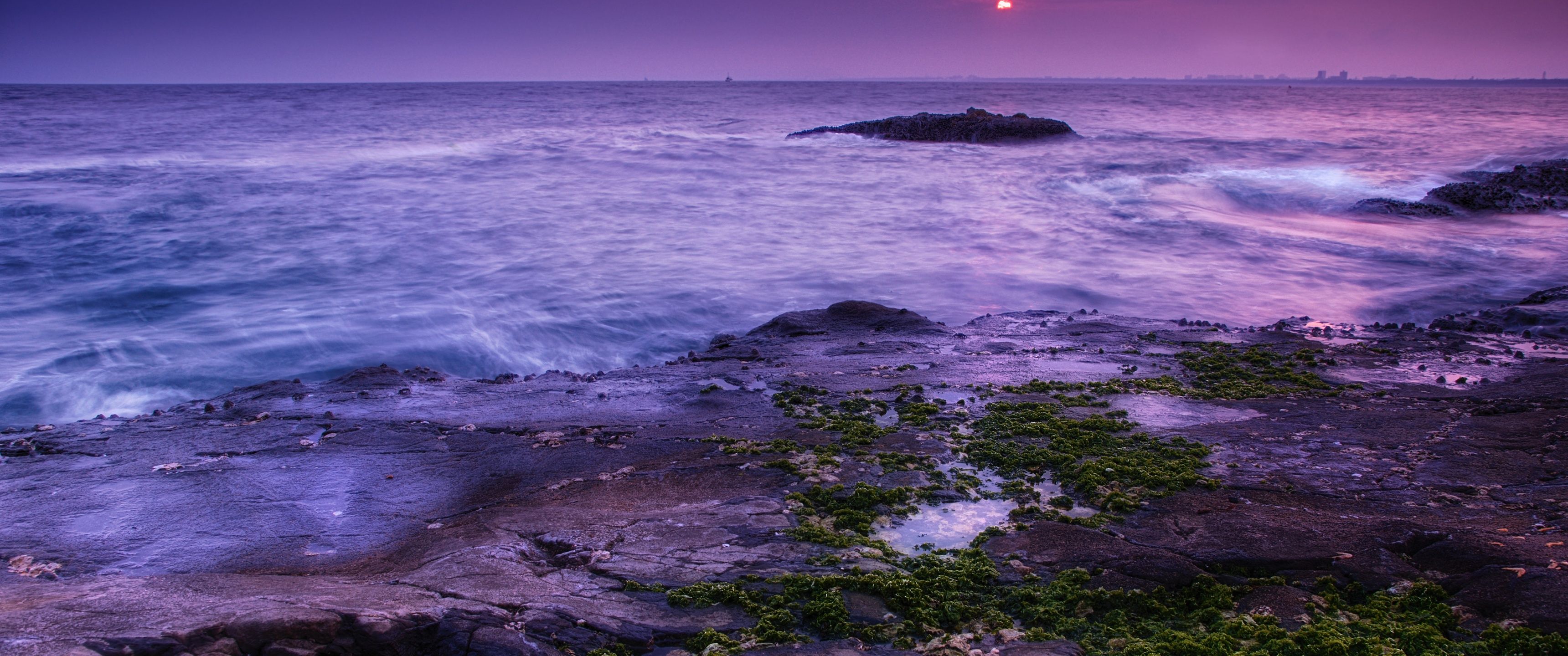 A rocky shore with water and the sun setting - Coast, ocean