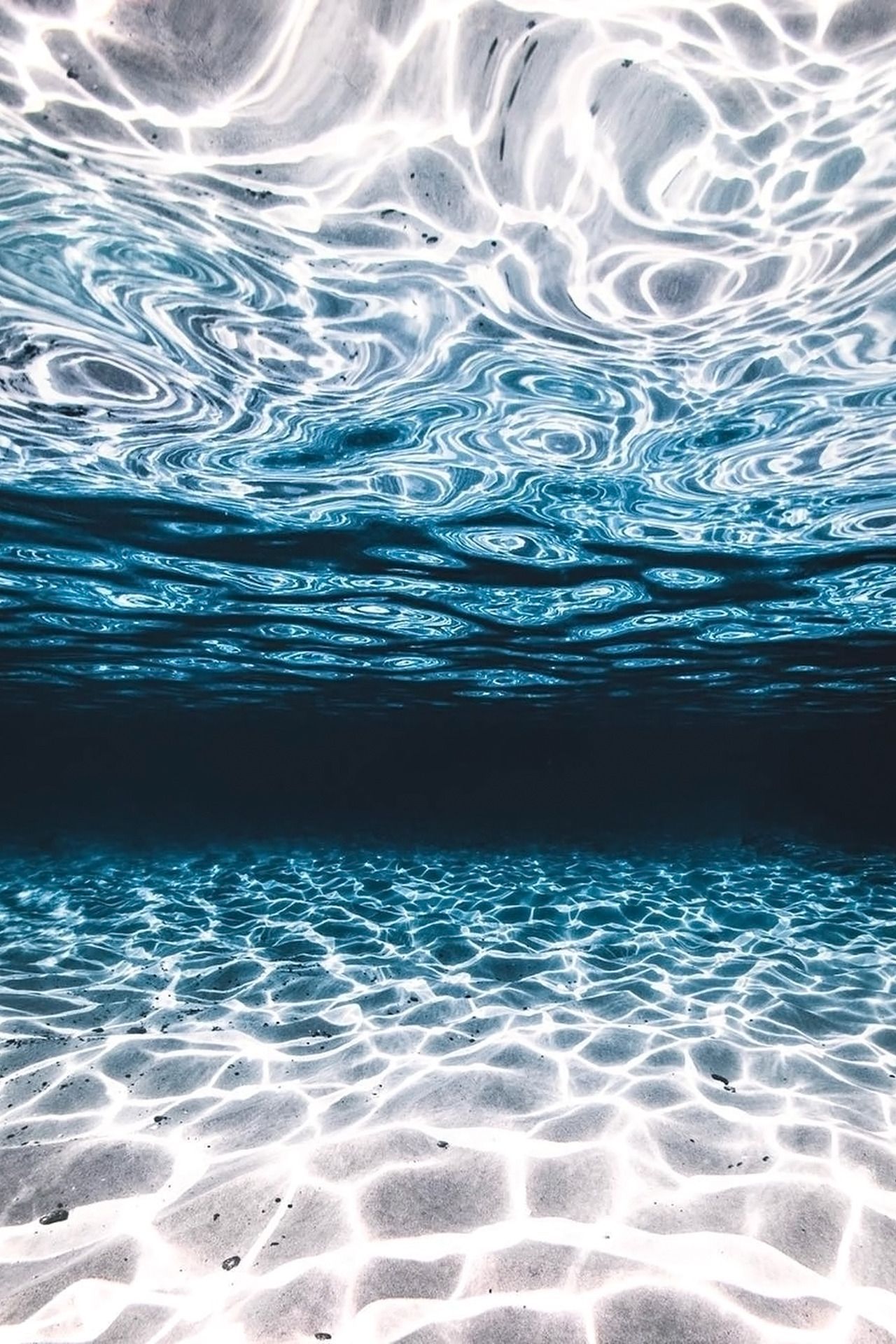 A photo of the ocean floor, with the sunlight shining through the water. - Ocean, water