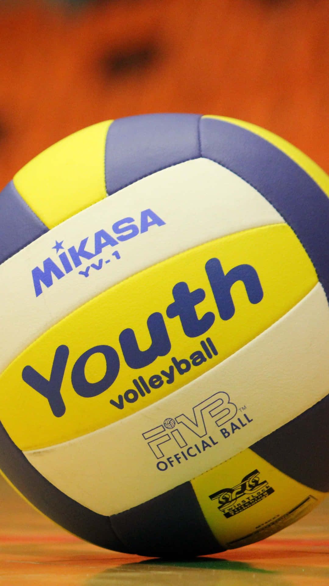 A Mikasa youth volleyball on a wooden floor. - Volleyball