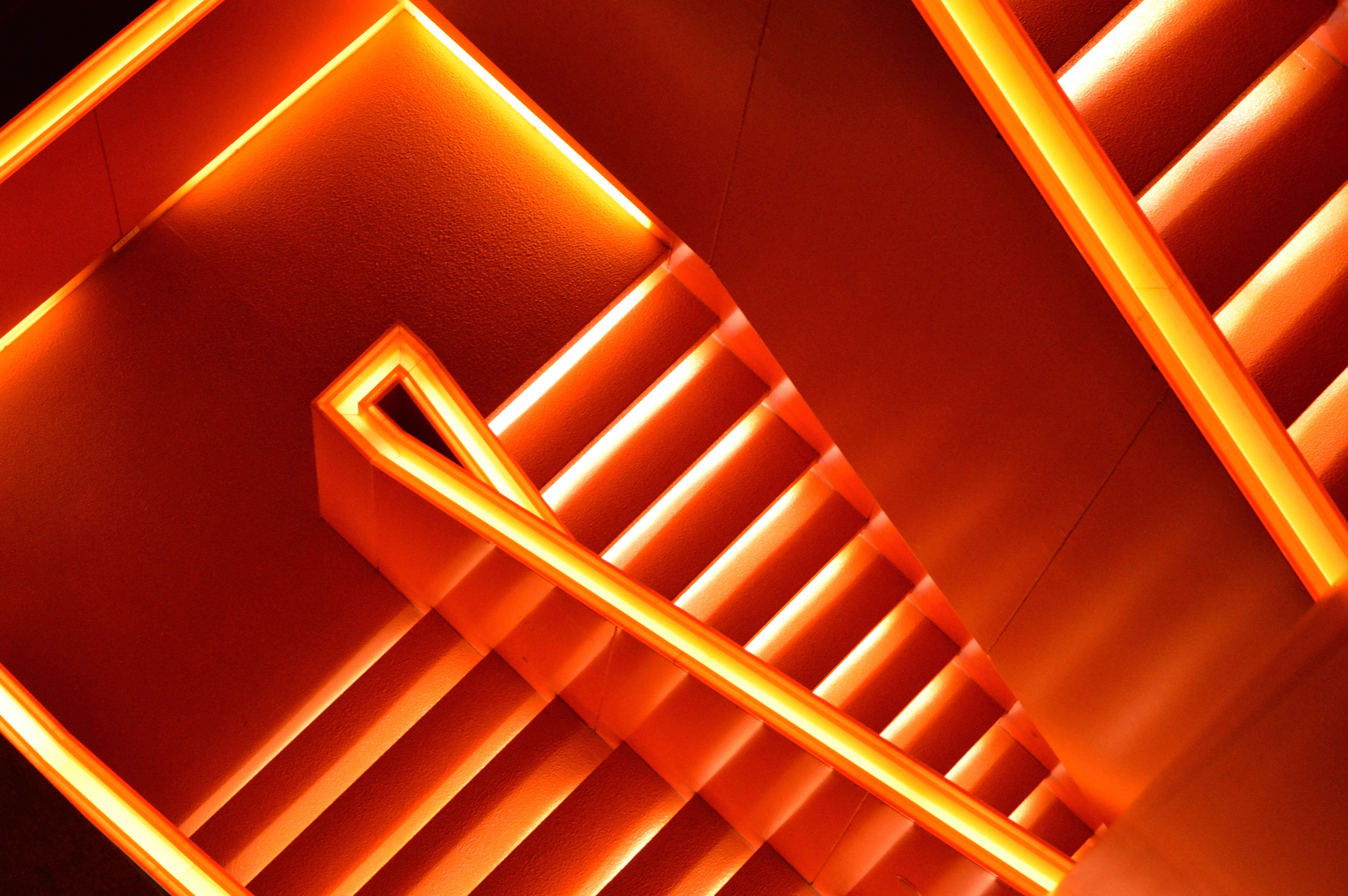A photograph of a staircase with orange lights. - Neon orange
