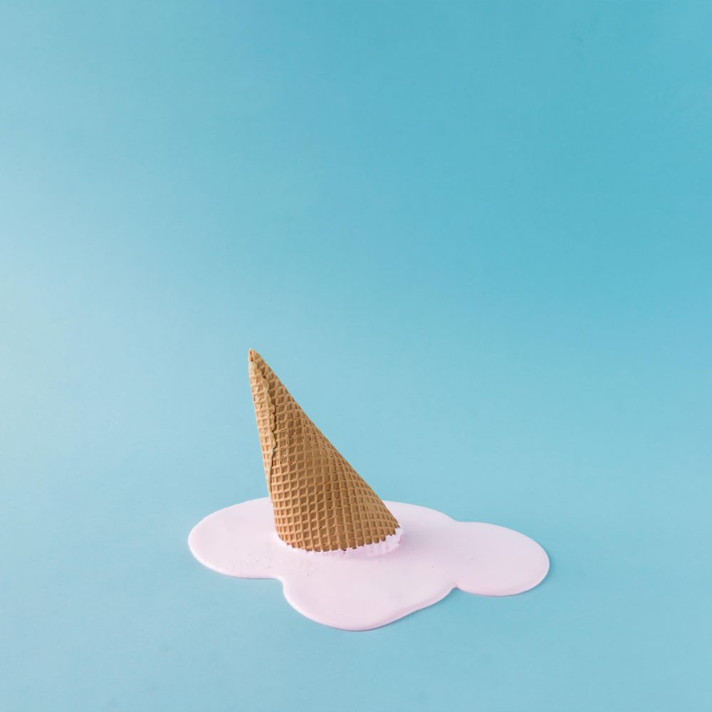 Melted pink ice cream and waffle cone on pastel blue background Photo (5qvqo4)