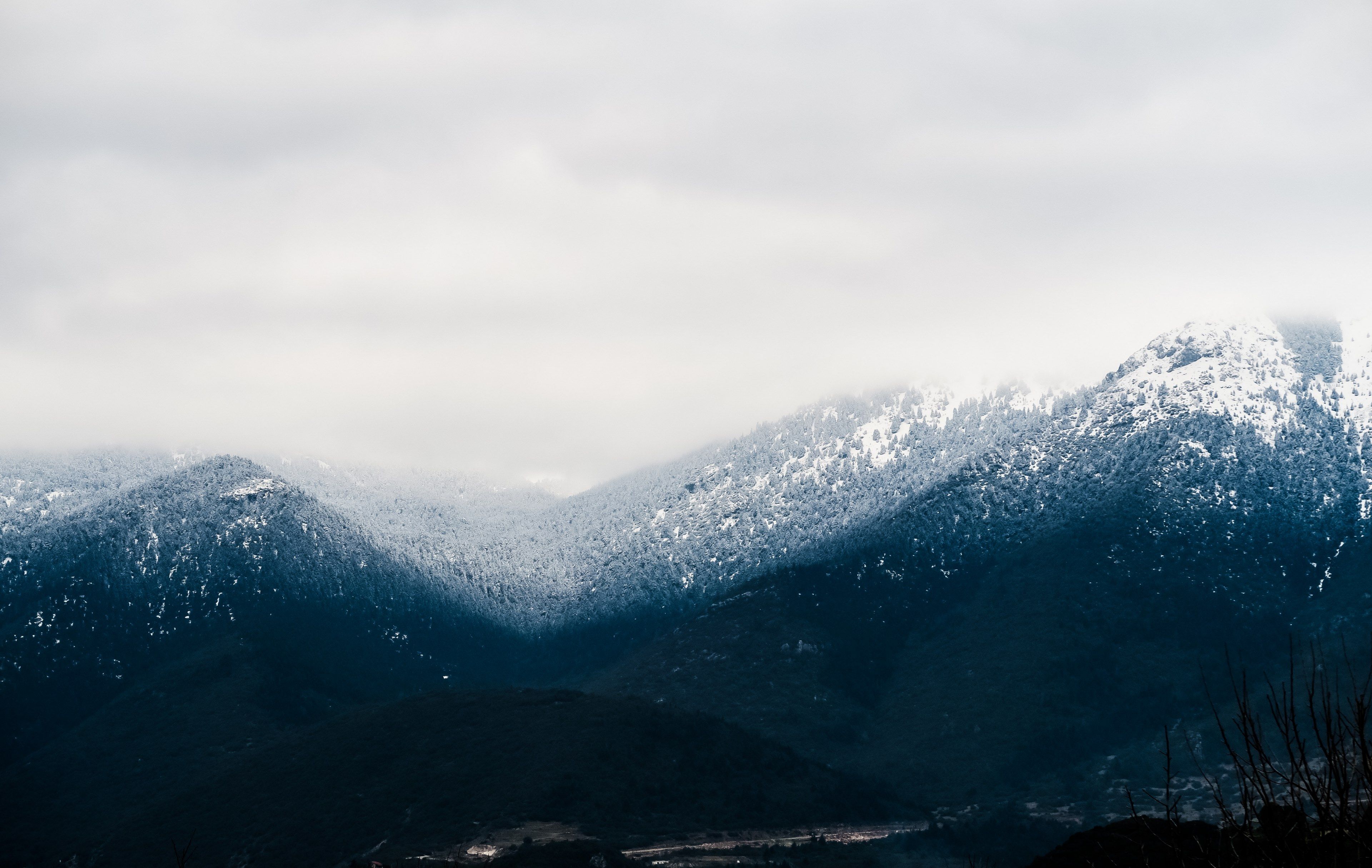 A snow-covered mountain range with a cloudy sky. - Mountain