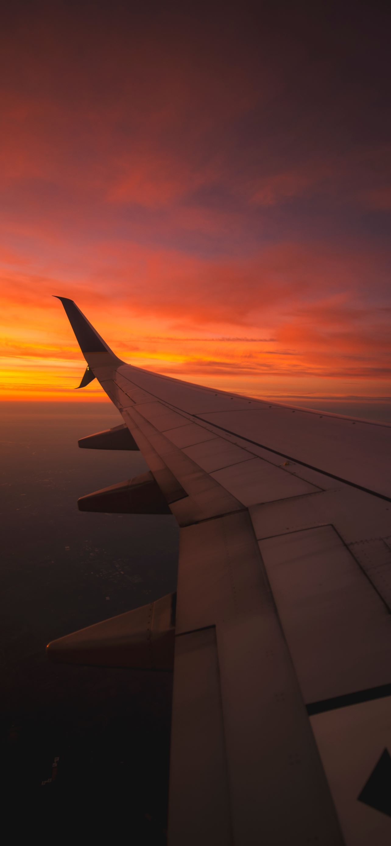 A wing of an airplane flying over the clouds - Travel