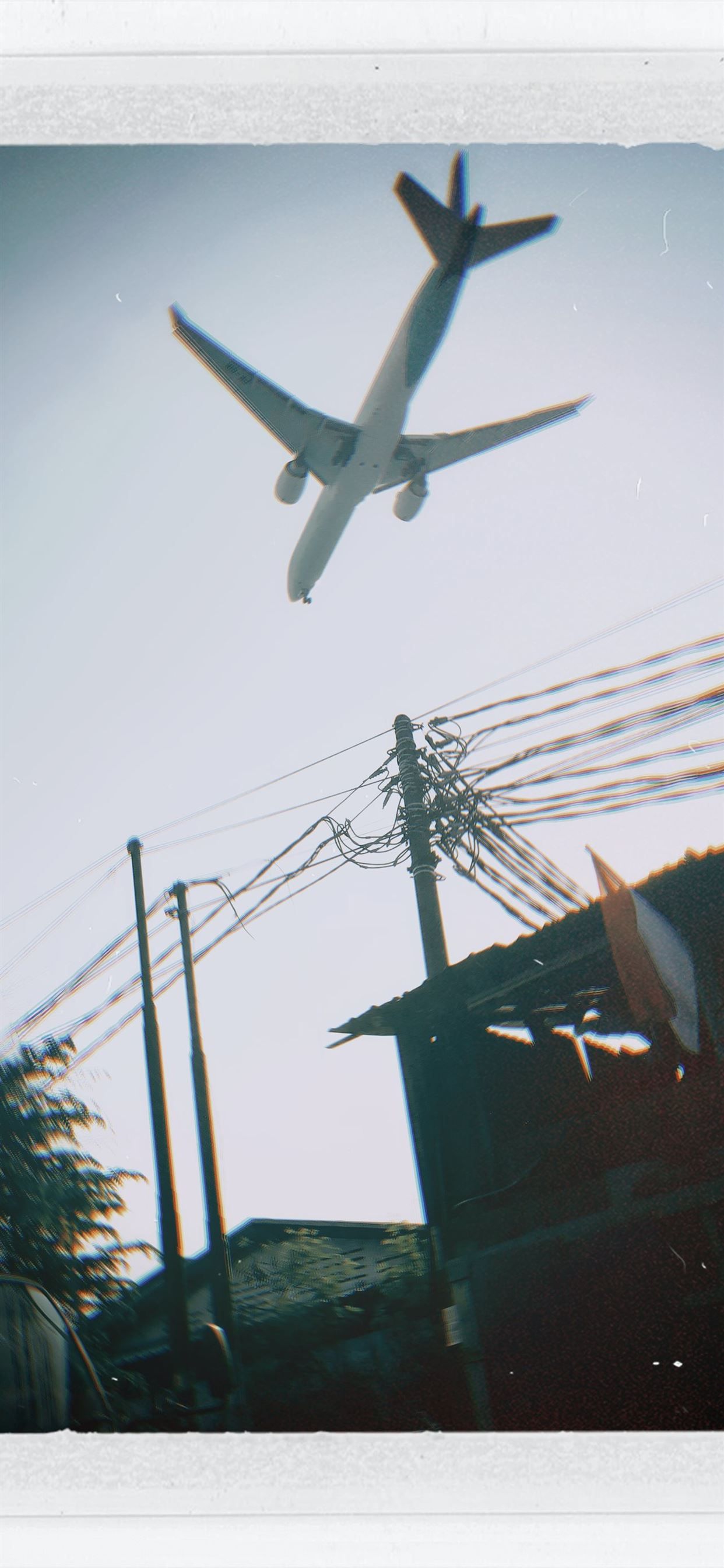 A plane flying over some buildings and power lines - Travel