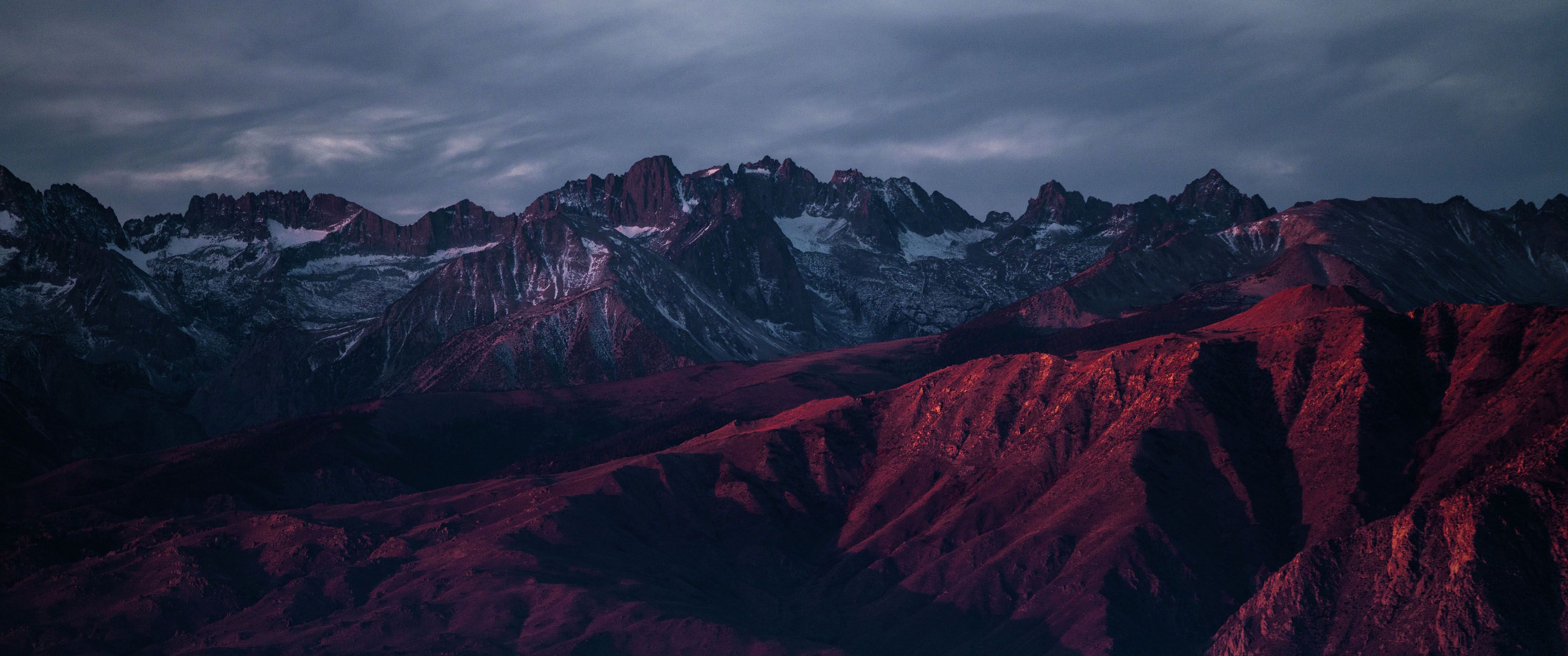 Red mountains at night with a cloudy sky - 3440x1440