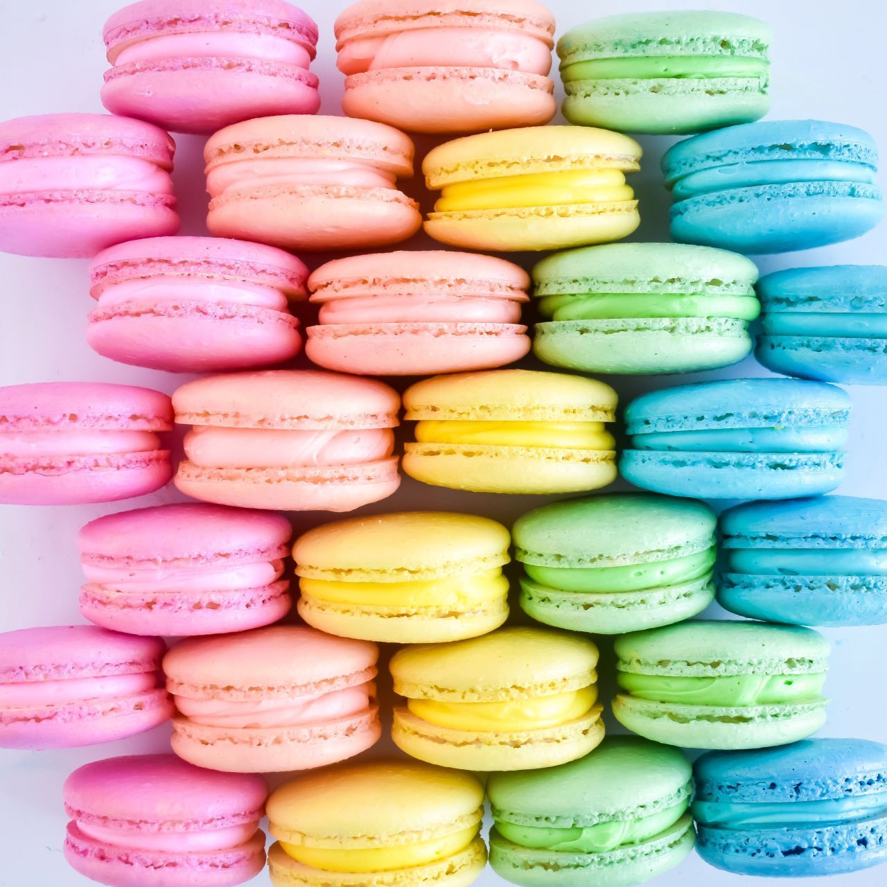 A colorful assortment of macarons stacked on top of each other. - Pastel rainbow