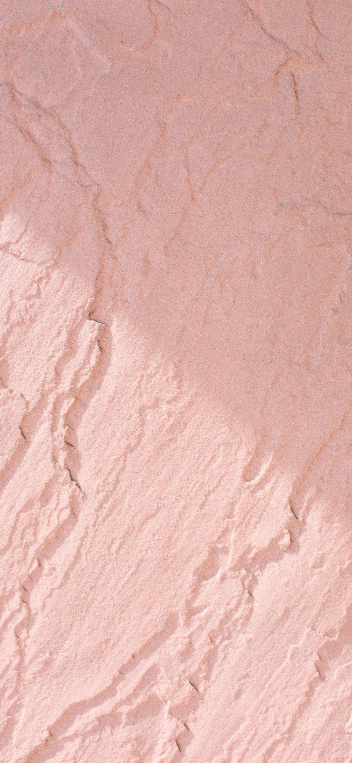 A close up of a pink stucco wall with cracks in it - Light pink