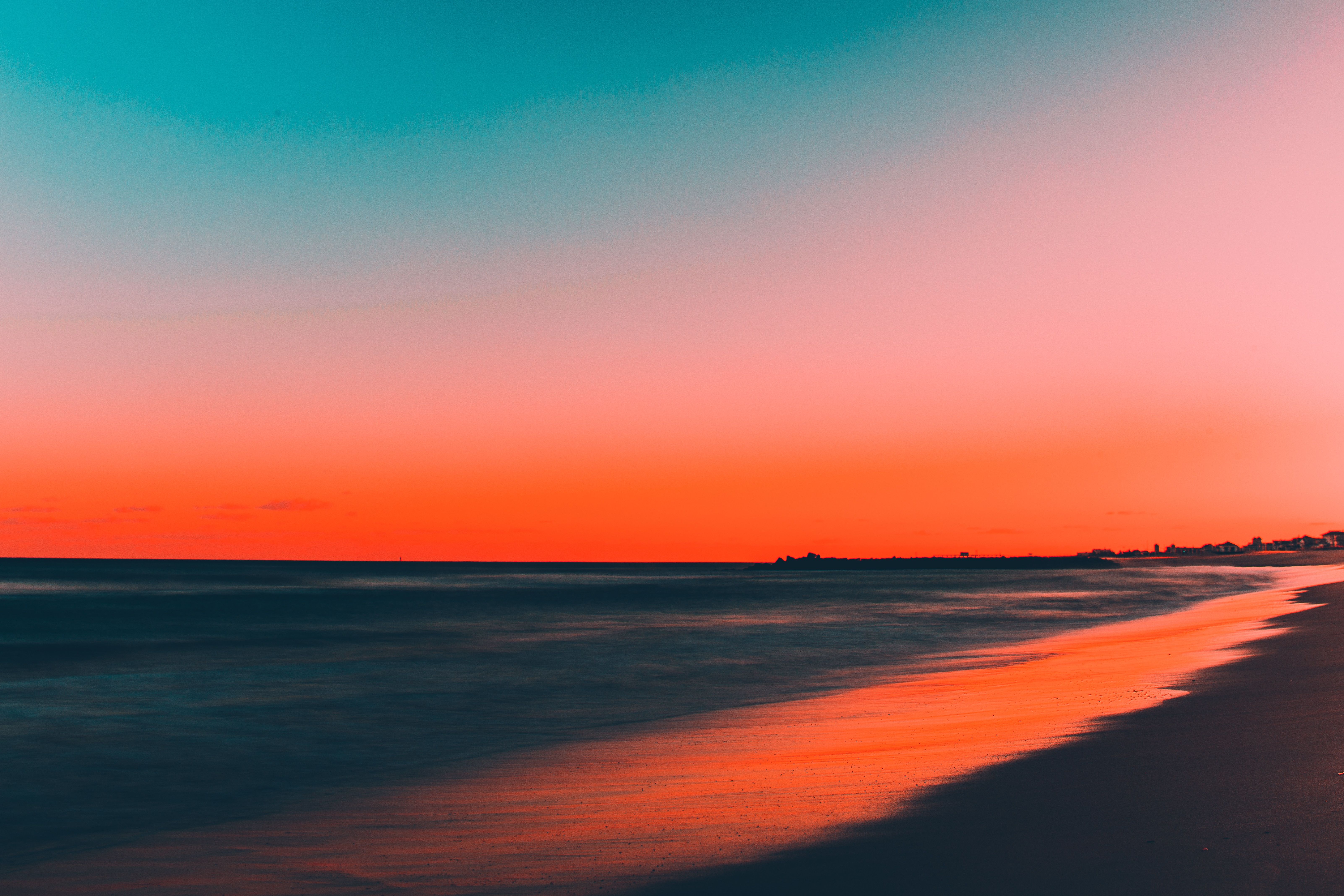 A beach at sunset with a blue and orange gradient sky. - Beach