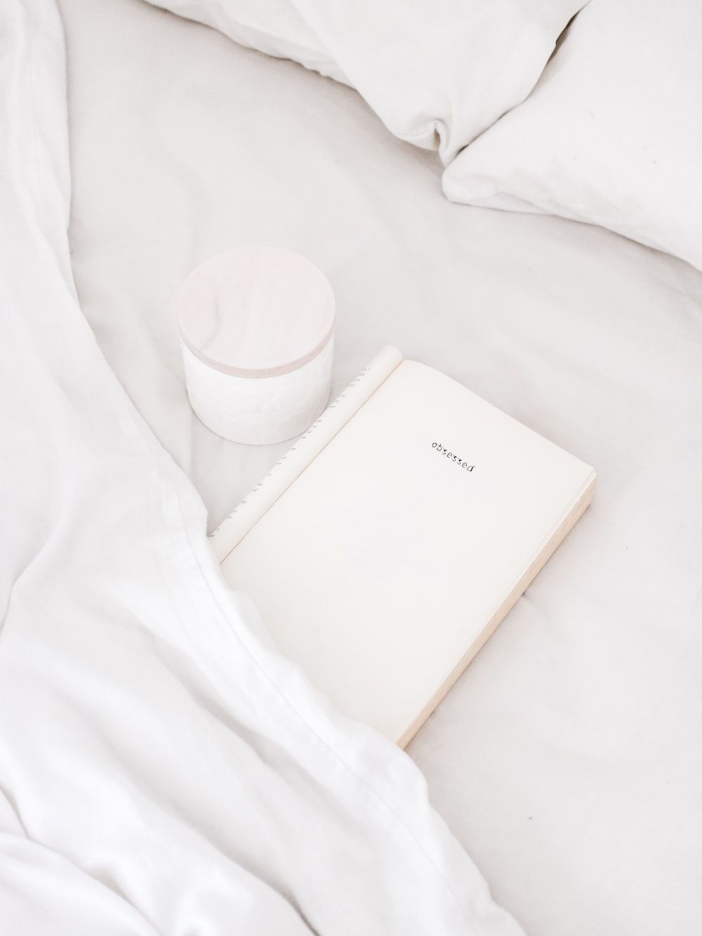 White notebook beside white cup on white bed sheet - White, cute white
