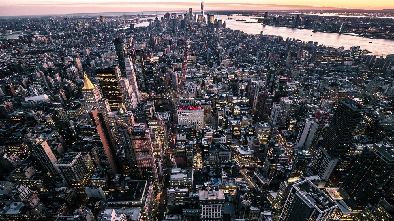 A city skyline at sunset with the buildings lit up - New York