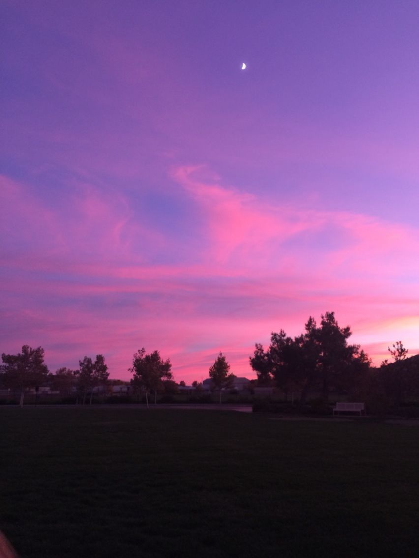A pink and purple sunset with a crescent moon in the sky. - Sad