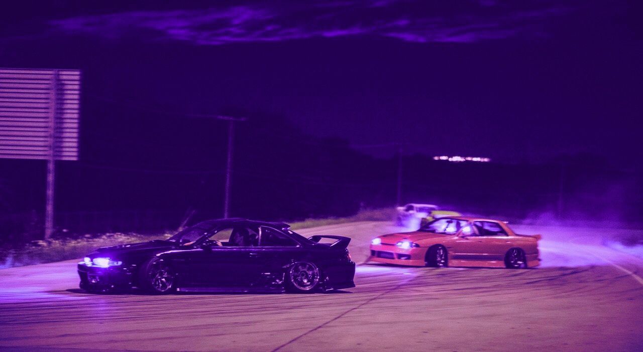 Two cars are drifting on a road at night. - JDM