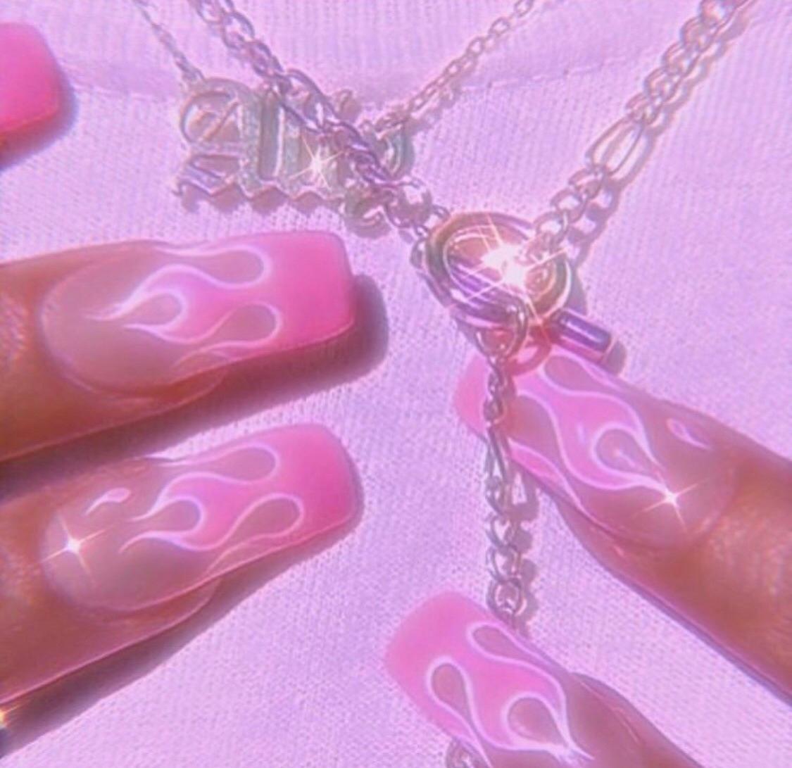 A person with pink nails holding up some jewelry - Baddie, nails