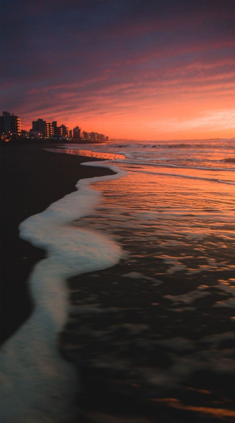 The beach at sunset with the city lights in the background - Sunset, sunrise, glitter
