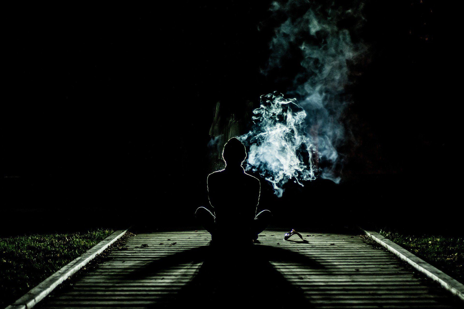 A person sitting on the ground with smoke coming from behind them - Smoke