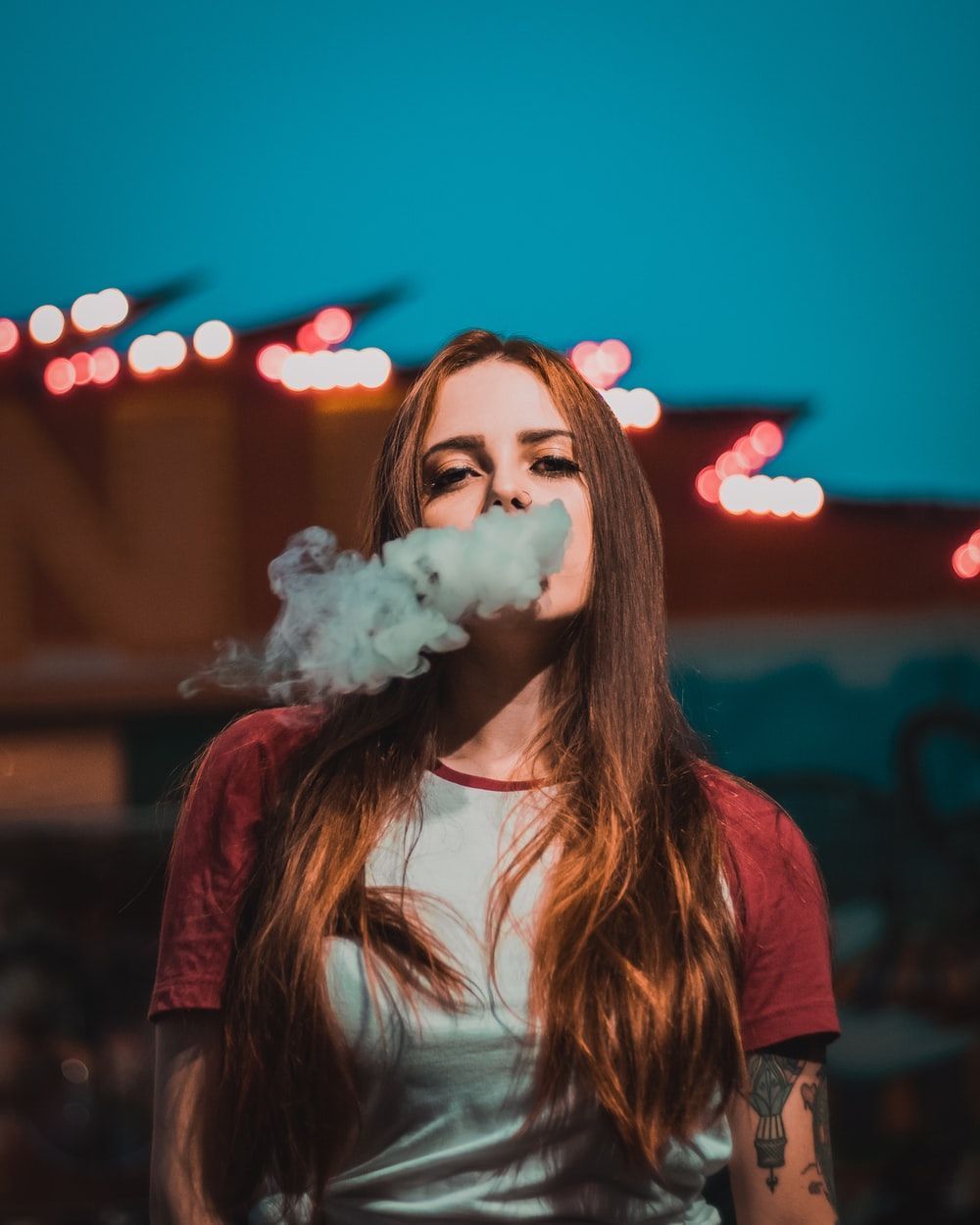 A woman with long brown hair blowing smoke from her mouth - Smoke