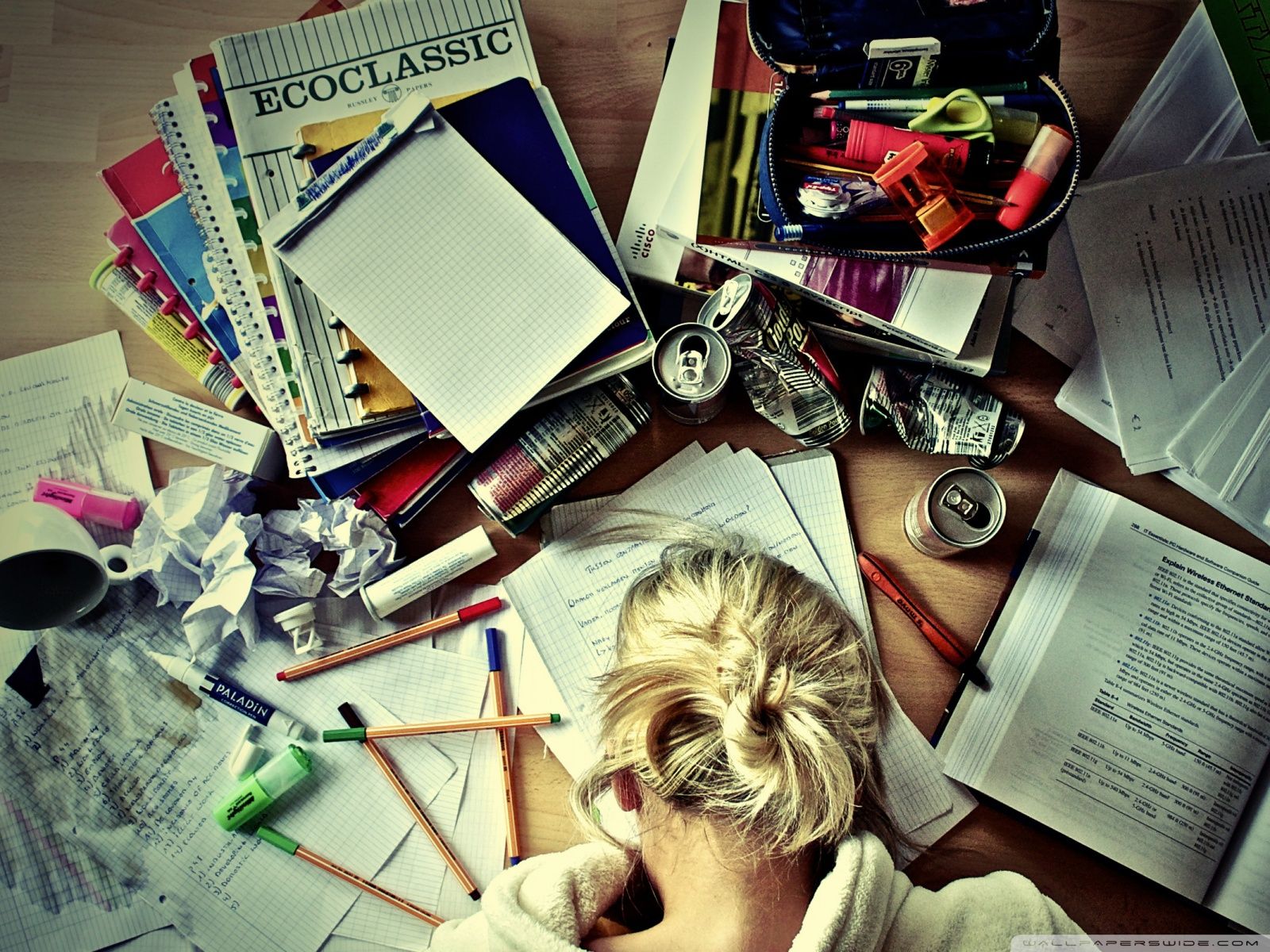 A woman with her head in her hands sitting at a cluttered desk - Study