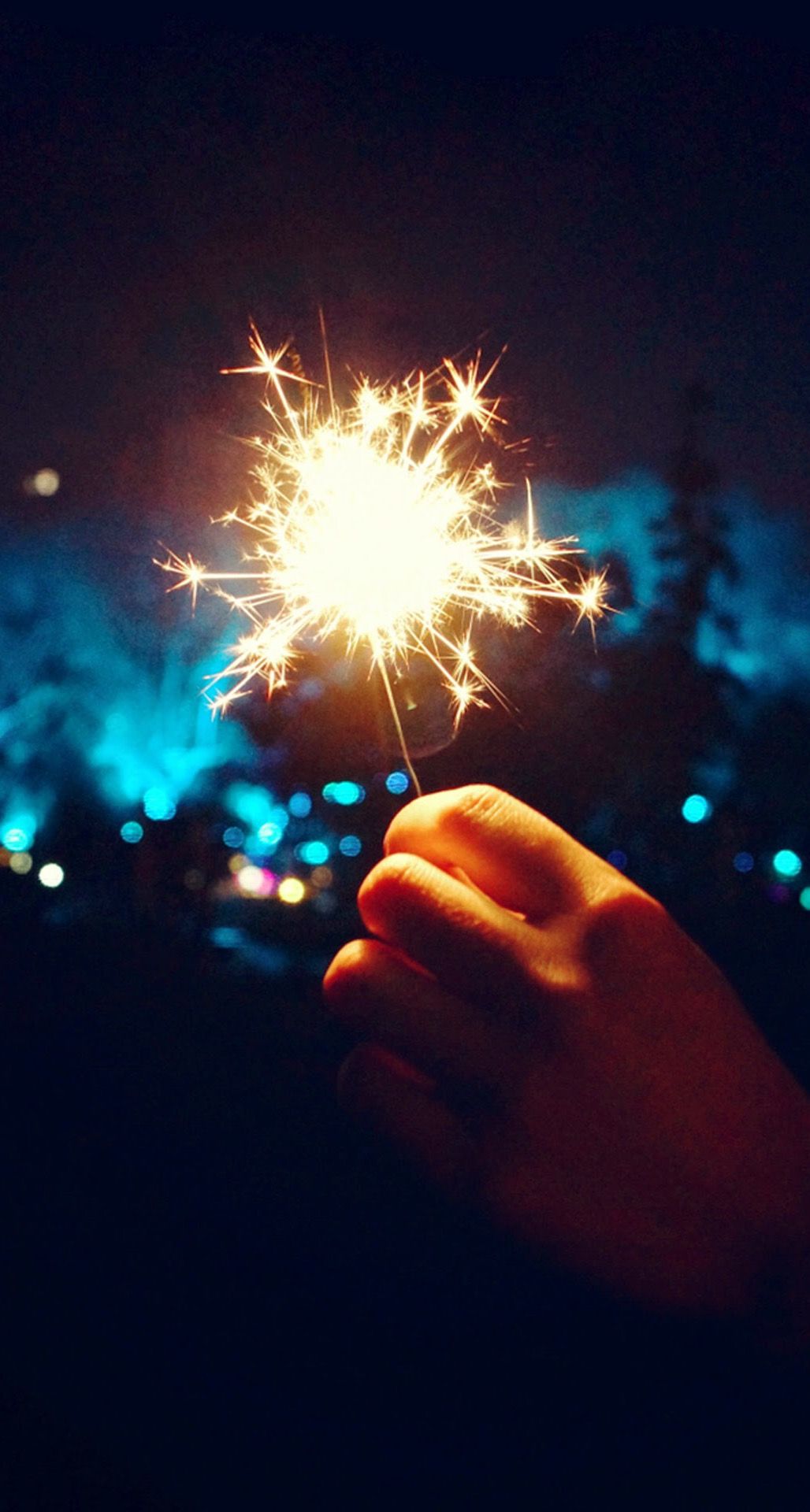A person holding up sparklers in the dark - New Year