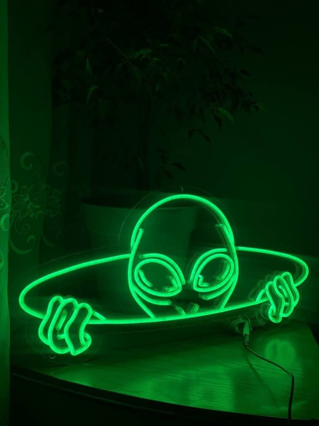 A neon sign of an alien on a skateboard. - Alien