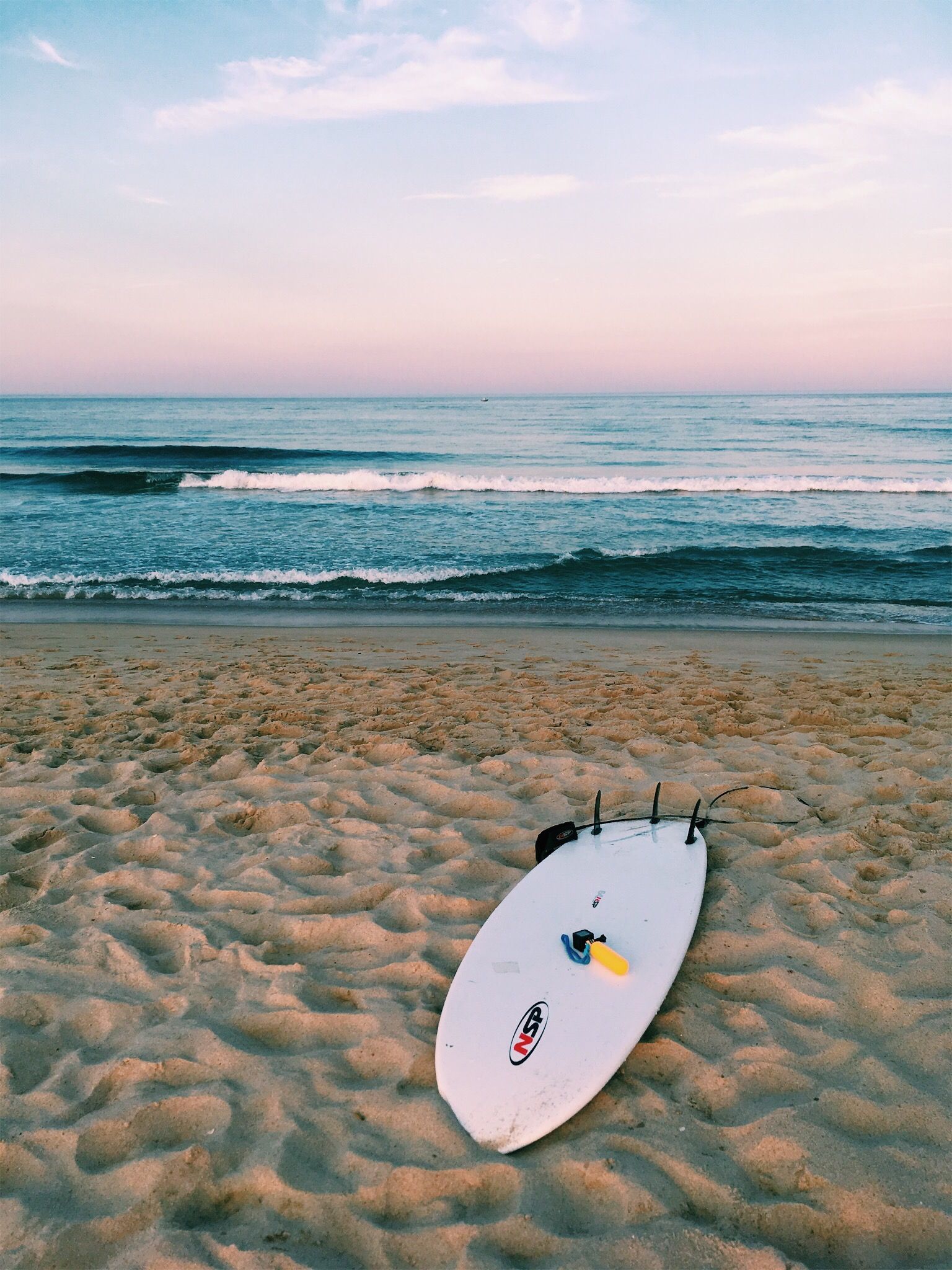 A surfboard laying on the beach at sunset - Surf