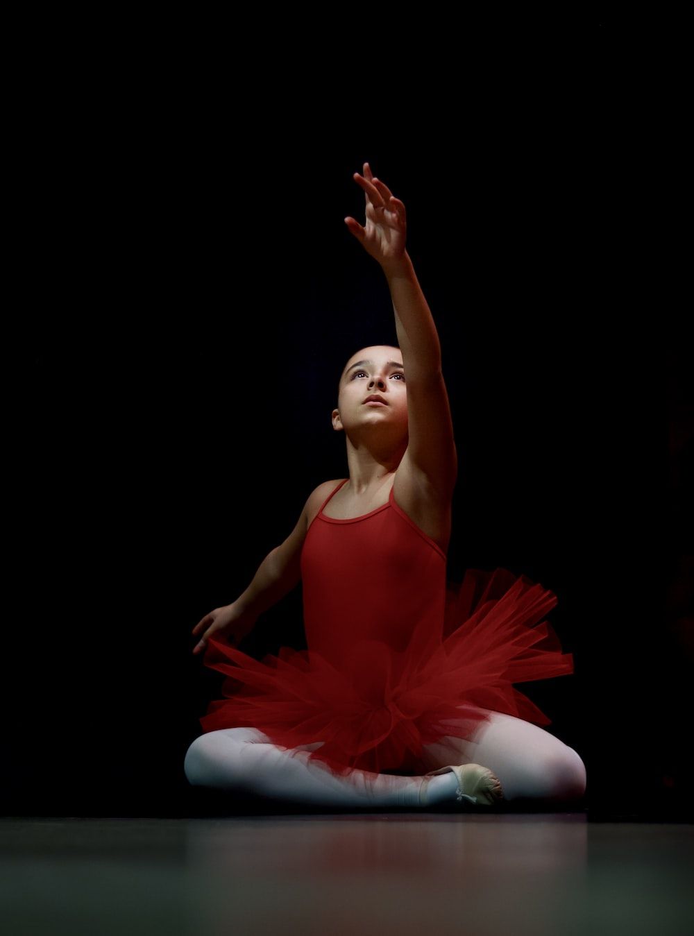 A young girl in red ballet outfit sitting on the floor - Ballet, dance