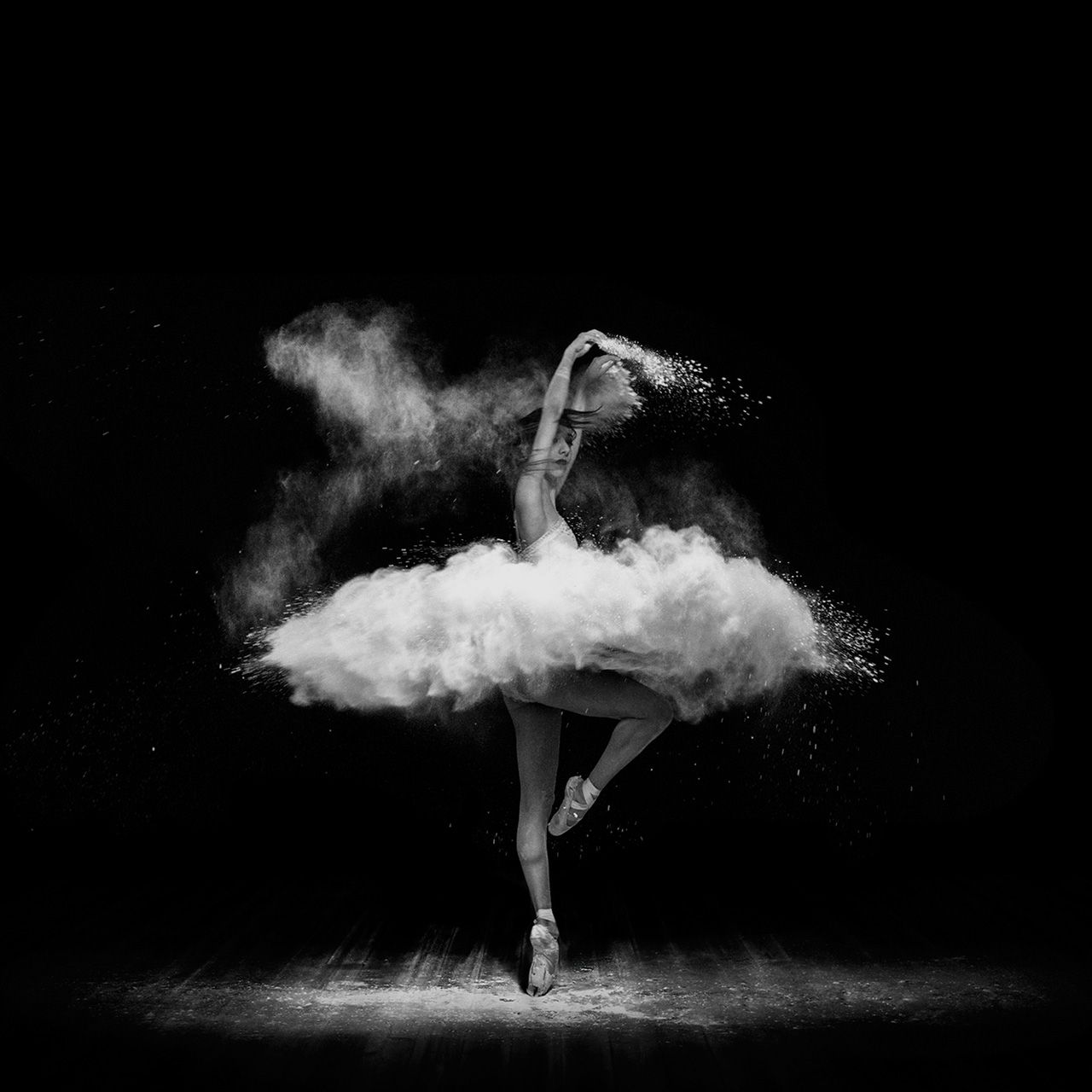 Black and white photo of a ballerina dancing with a cloud of flour behind her. - Ballet