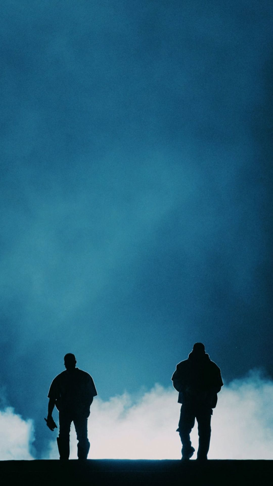 Two men standing on a hill with smoke in the background - Drake