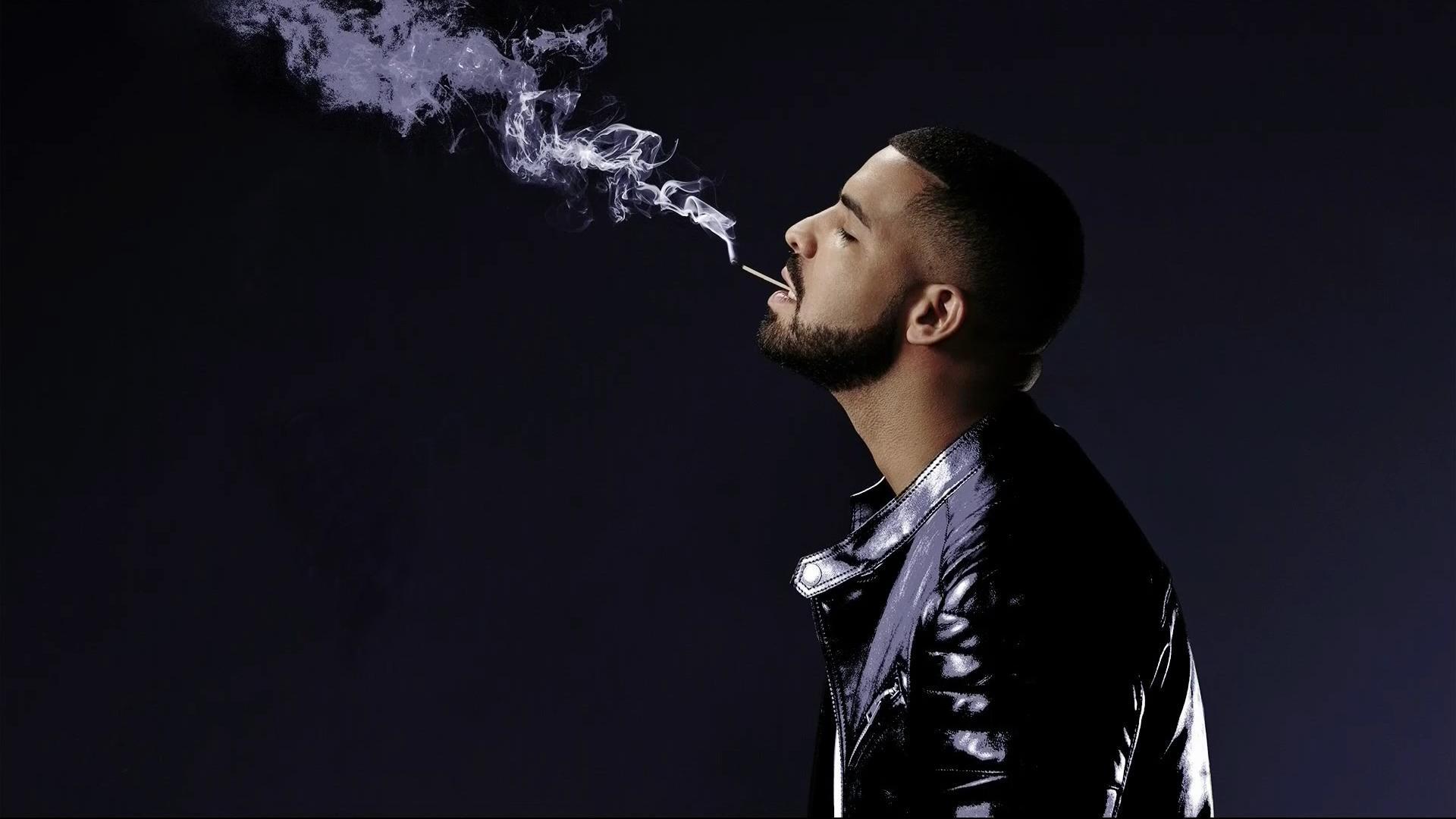 Rapper Drake blowing smoke in the air in front of a black background - Drake