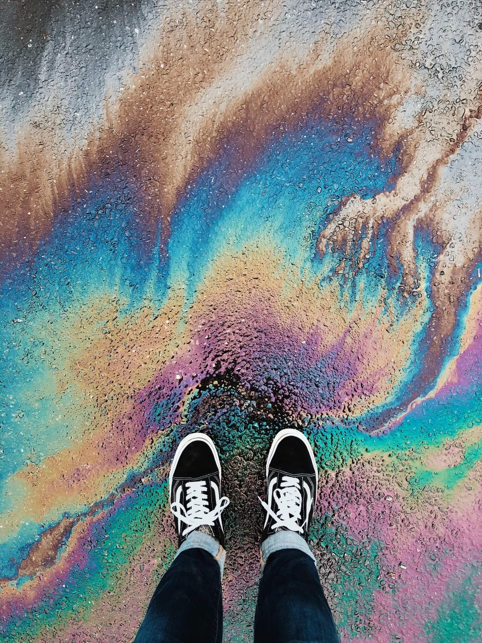 A person's feet standing on a rainbow oil slick - Magic