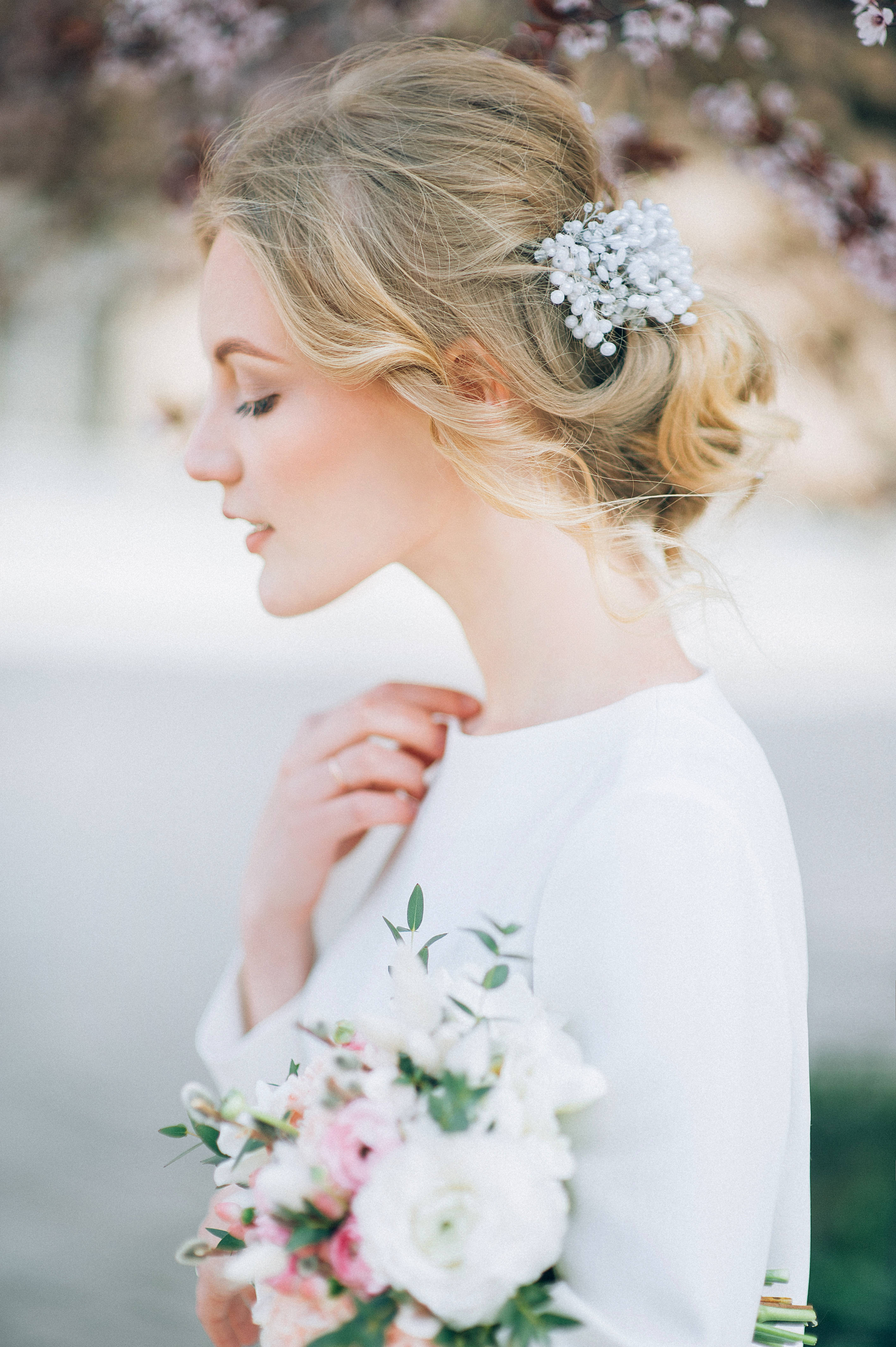 A woman in white holding flowers and wearing jewelry - Wedding