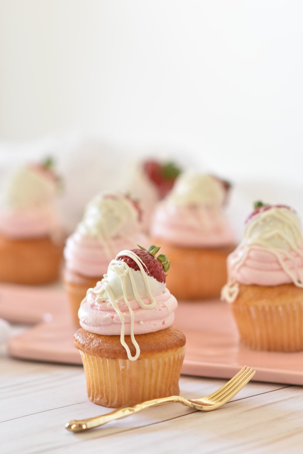 Strawberry cupcakes with white chocolate drizzle and a fresh strawberry on top. Perfect for Valentine's Day or any special occasion. - Bakery, cake