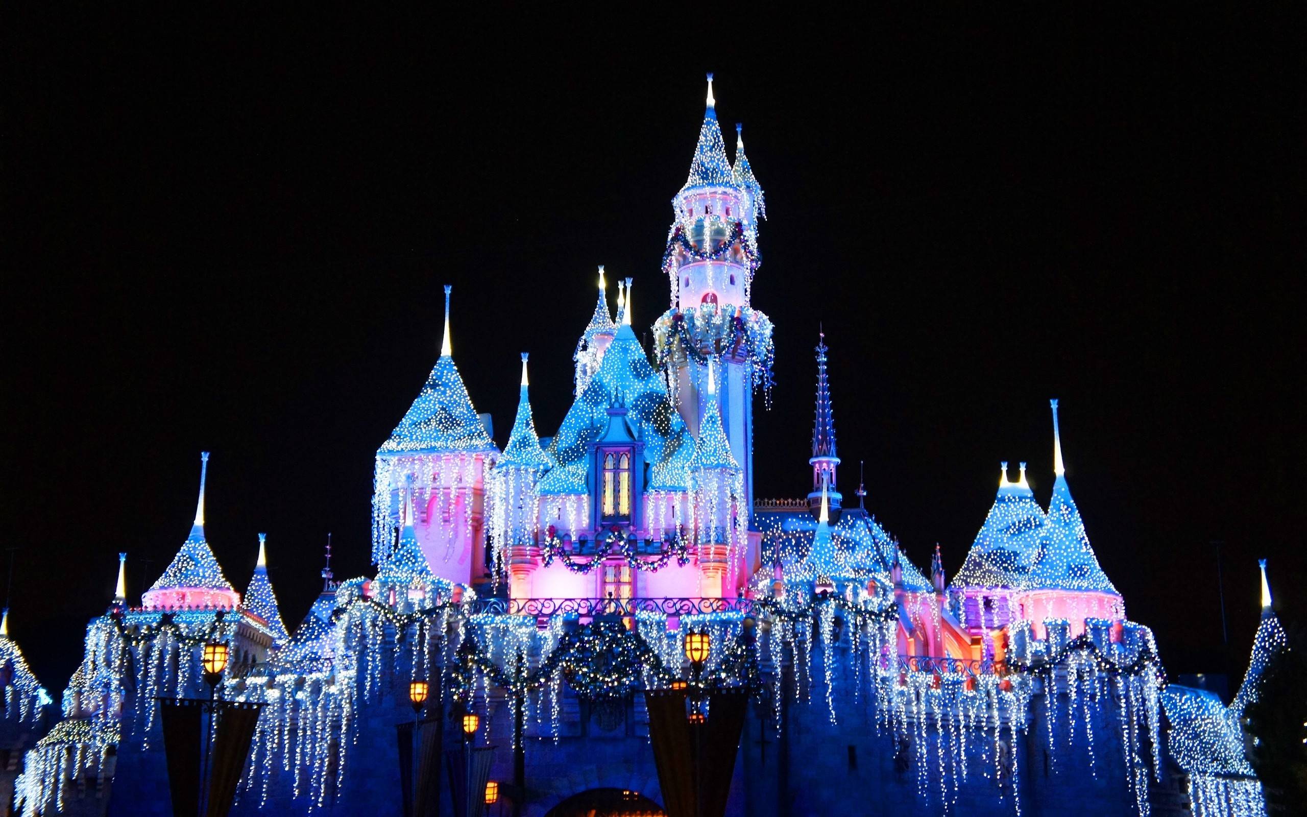 The castle at Disneyland is lit up with blue lights. - Castle