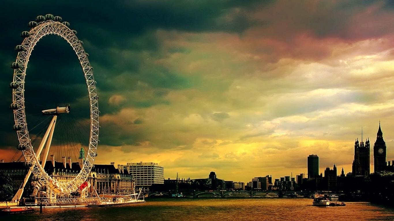 A large ferris wheel on the water in front of a city. - London