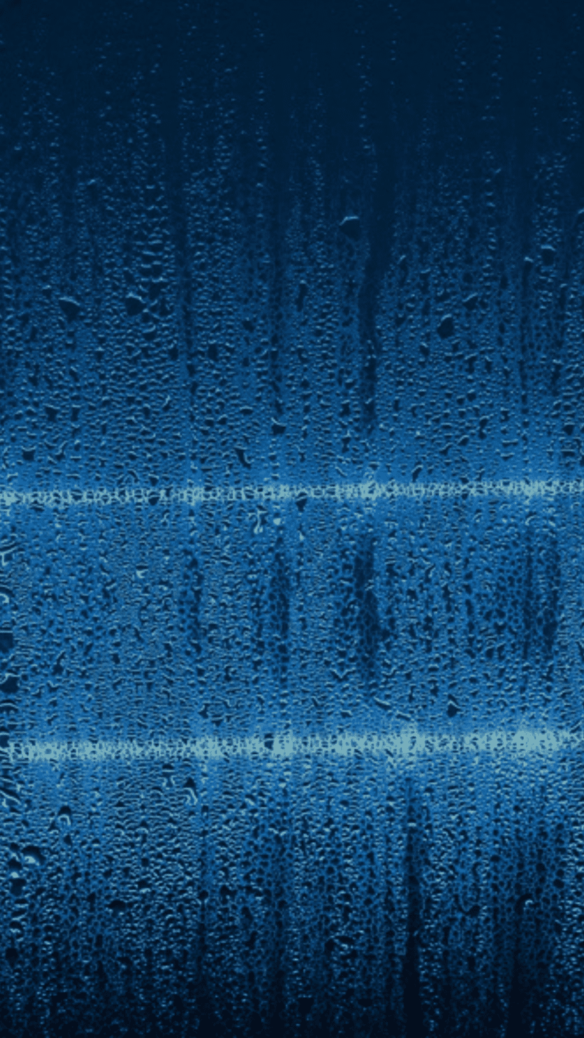 A close up of water droplets on a window, with a blue hue. - Blue